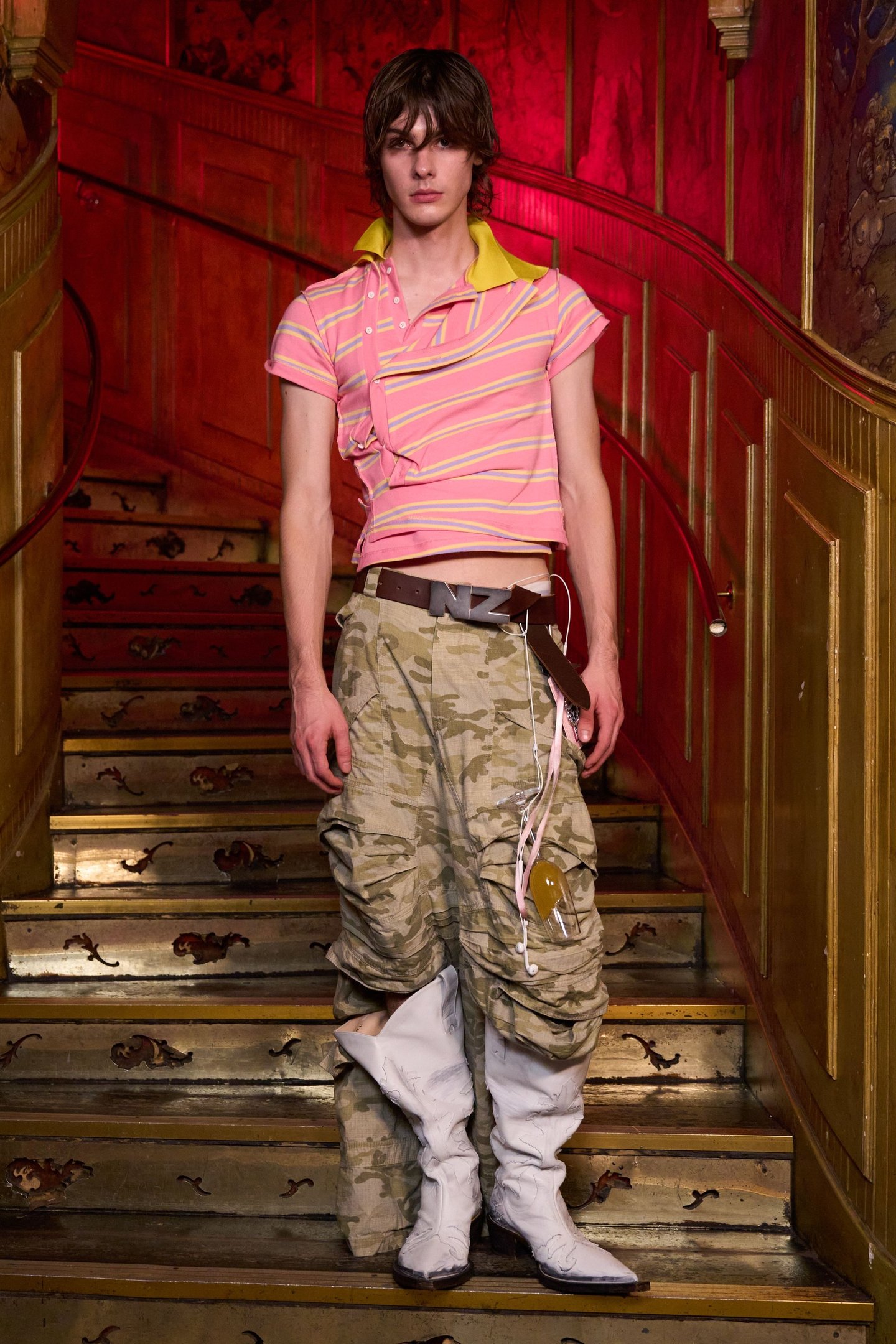 Modelo com camisa polo listrada rosa e calça cargo camuflada na London Fashion Week SS26.