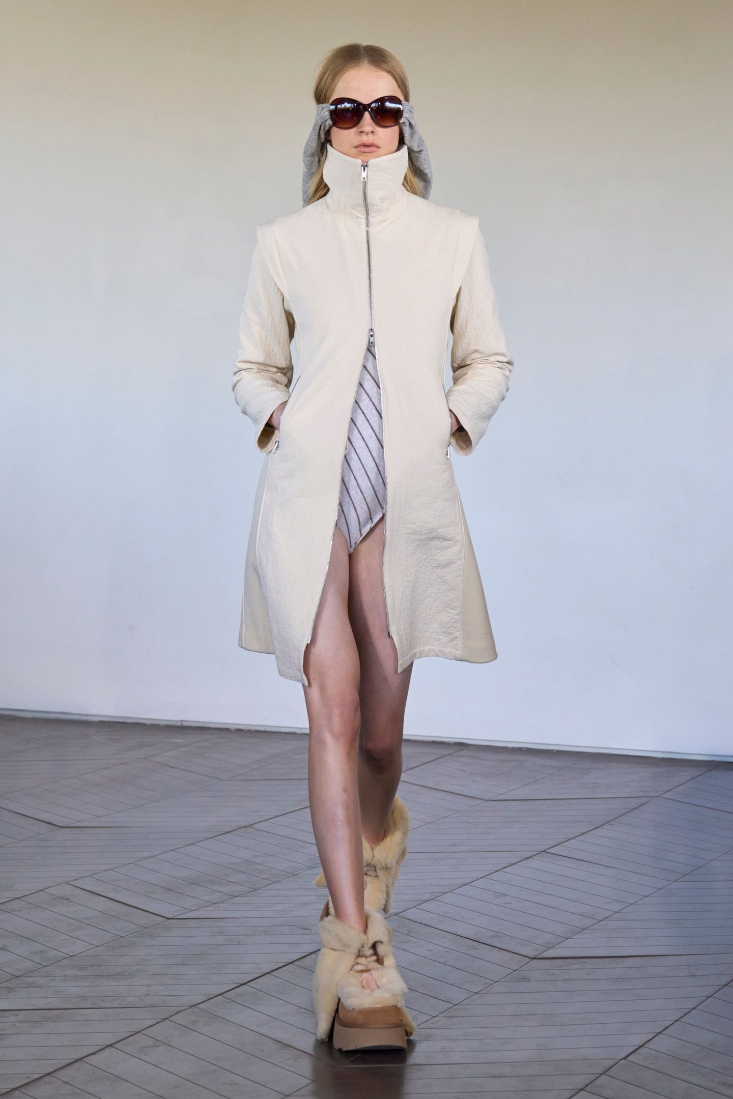 Modelo desfila com casaco bege e sapatos de plataforma felpudos na London Fashion Week SS26.