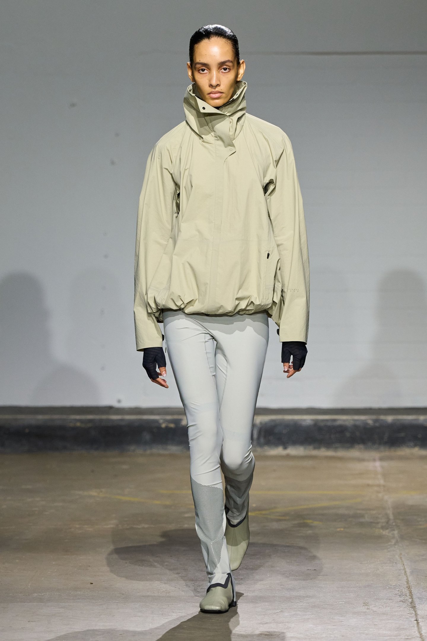 Modelo com casaco e calça bege na passarela da London Fashion Week SS26.