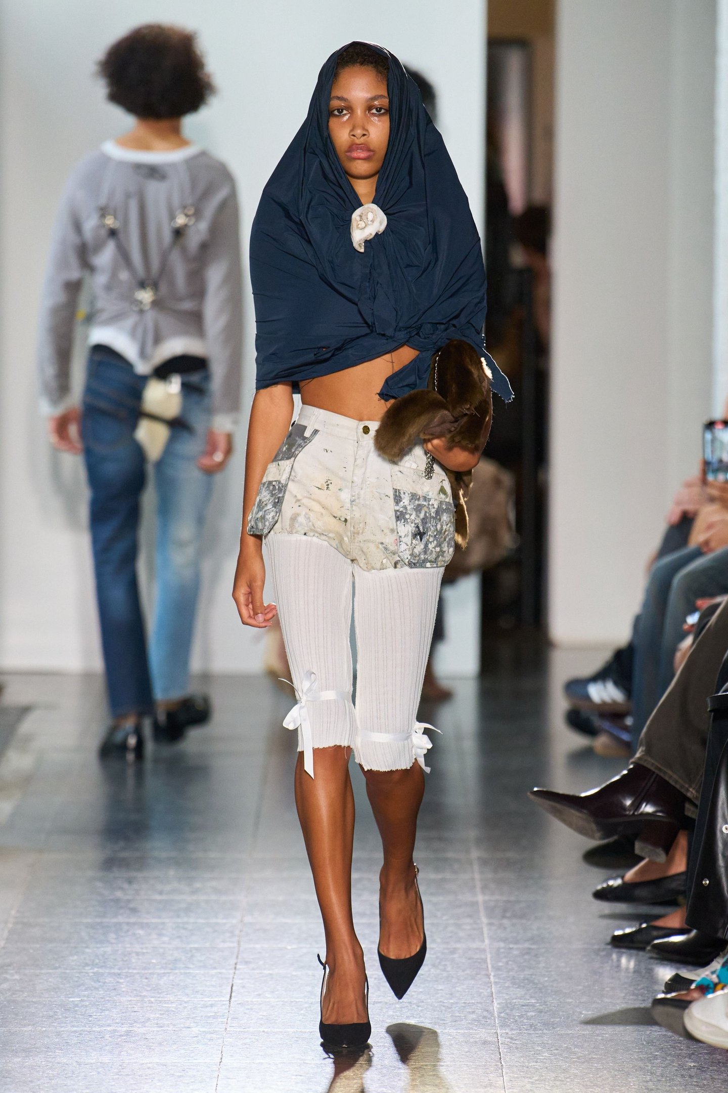 Modelo caminha na passarela com peça estilizada e capa no London Fashion Week SS26.