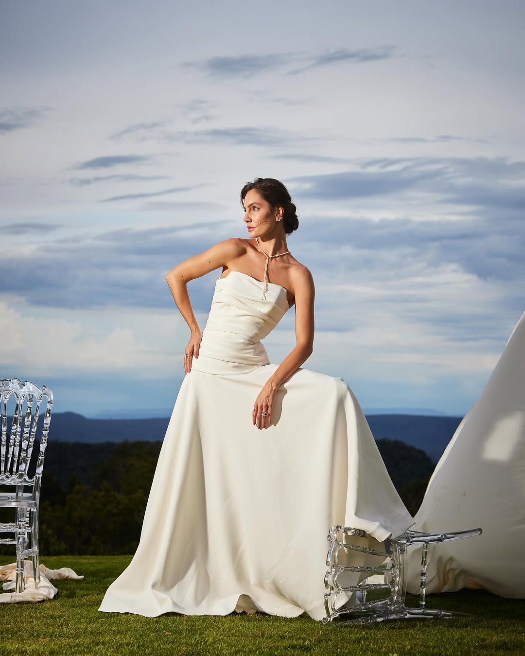 Vestido de noiva elegante em cenário ao ar livre, refletindo o estilo sofisticado de Lucas Anderi.