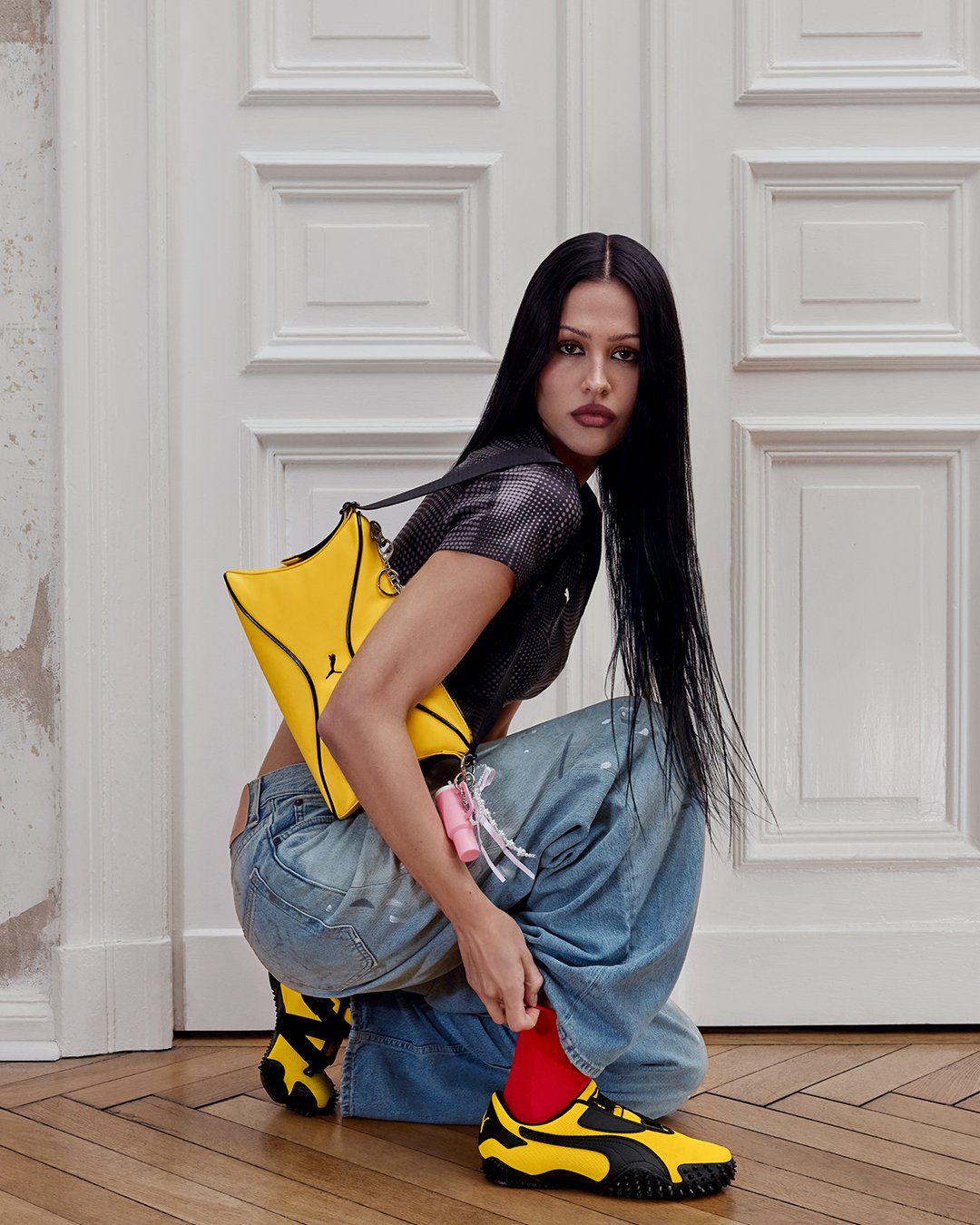 Mulher agachada com bolsa e tênis amarelos da PUMA, destacando tendência de cores vibrantes.