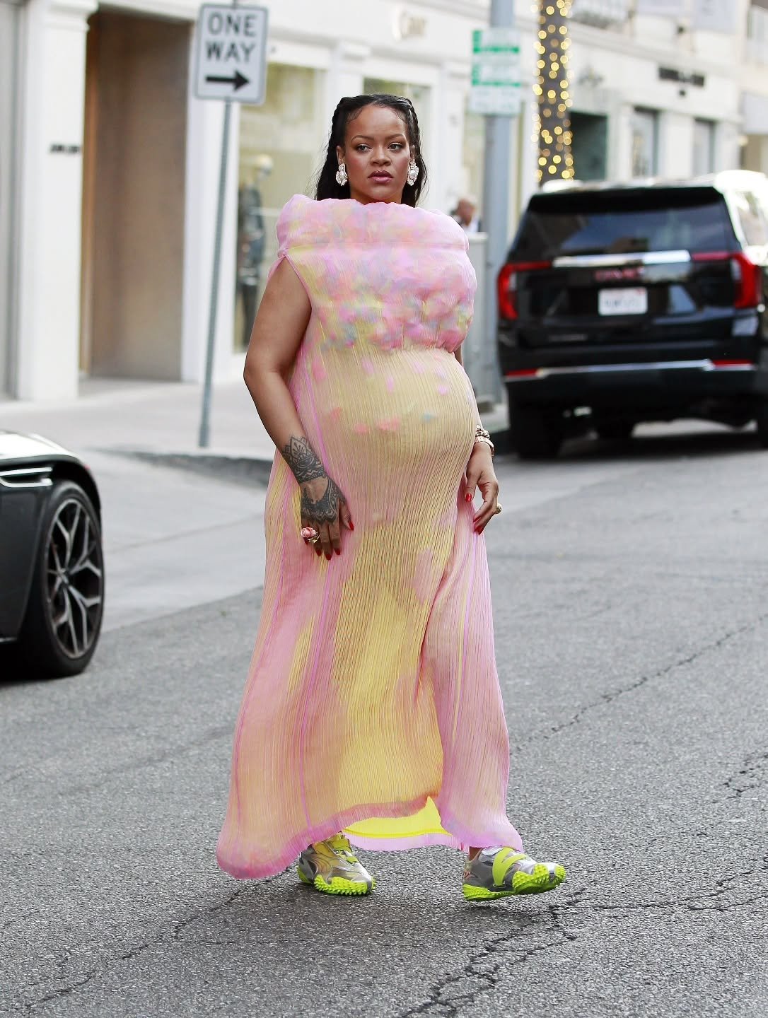 Pessoa usando vestido rosa e amarelo, com tênis tendência da PUMA verdes, em rua urbana durante o dia.