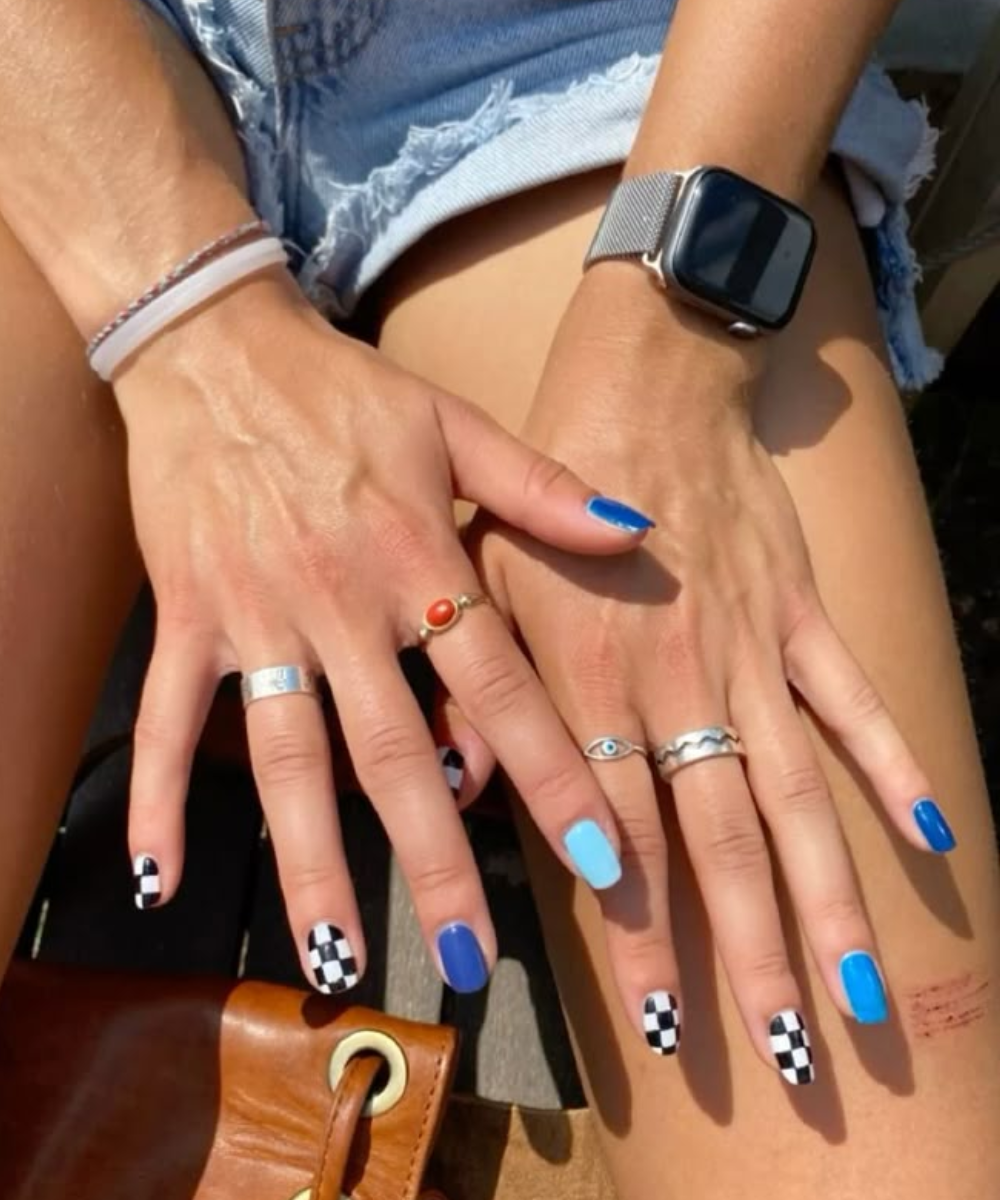 Unhas decoradas com tema de Fórmula 1, exibindo padrões de bandeira quadriculada e esmalte azul.