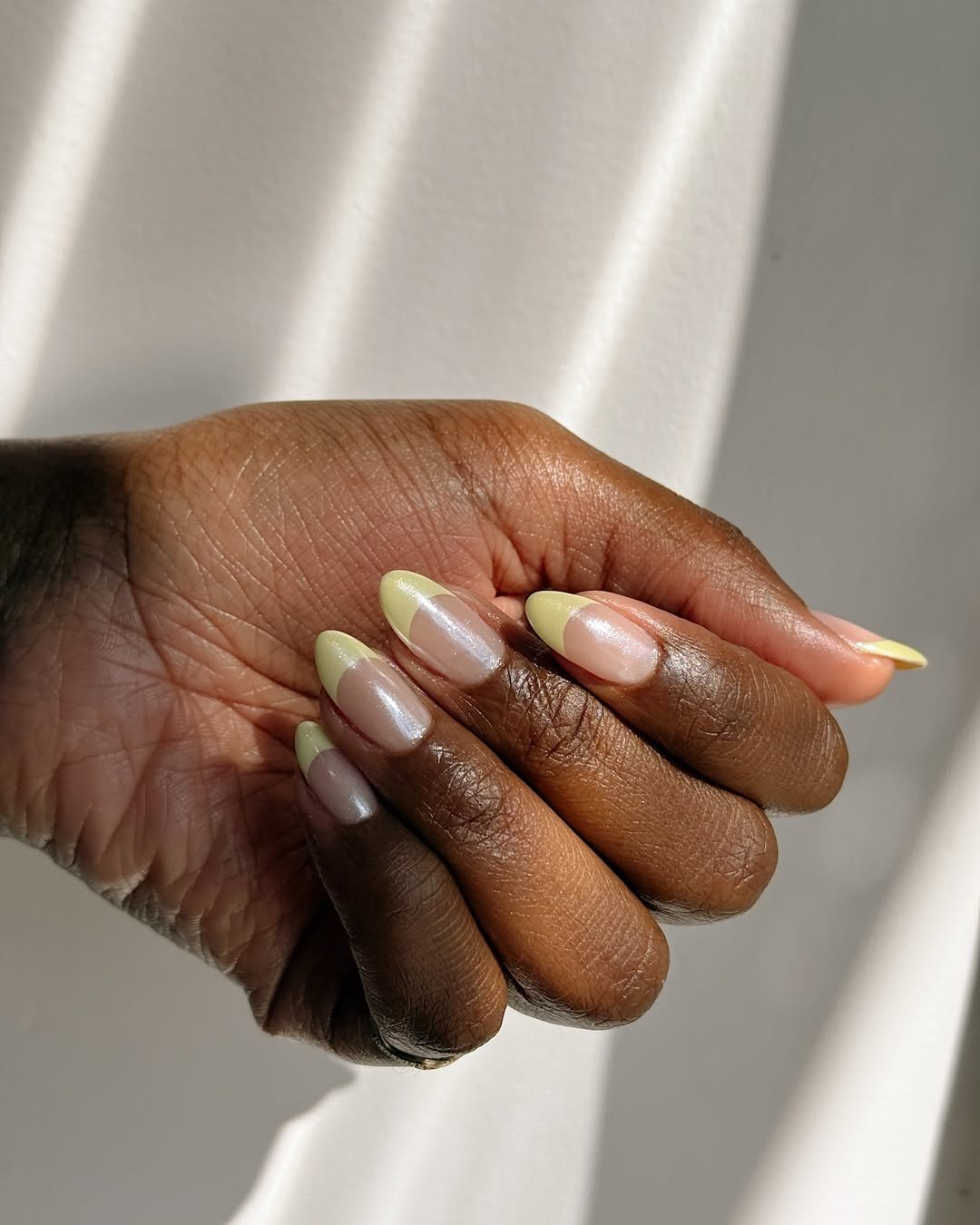 Unhas com esmalte amarelo claro, translúcido e elegante, com um design ideal para a primavera.