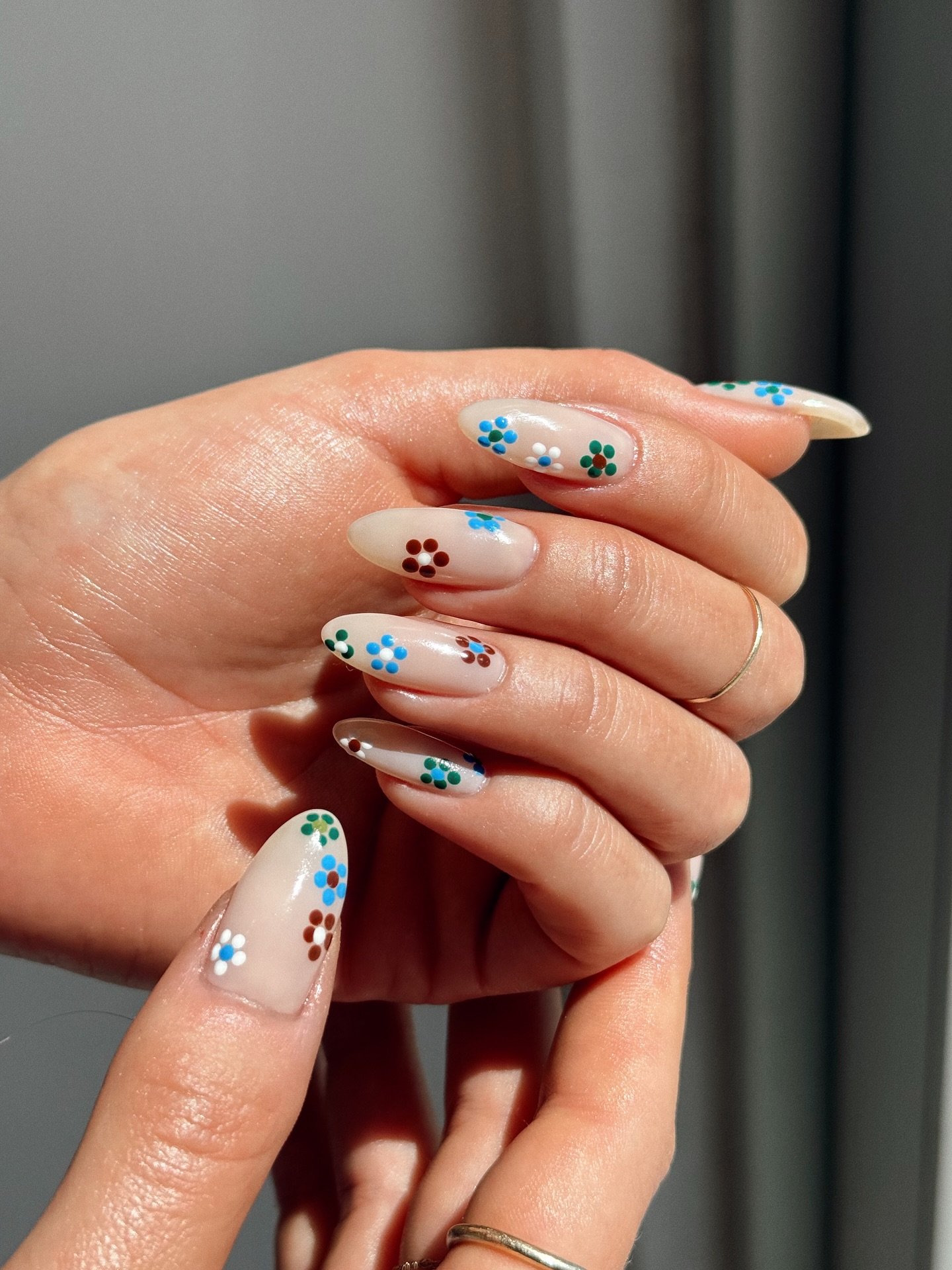 Unhas decoradas com pequenas flores coloridas, estilo primavera.