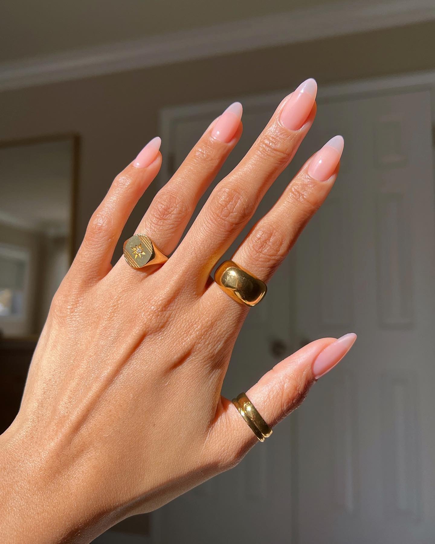 Unhas para primavera elegantes em tom rosa claro com acessórios dourados, evocando estilo primavera.