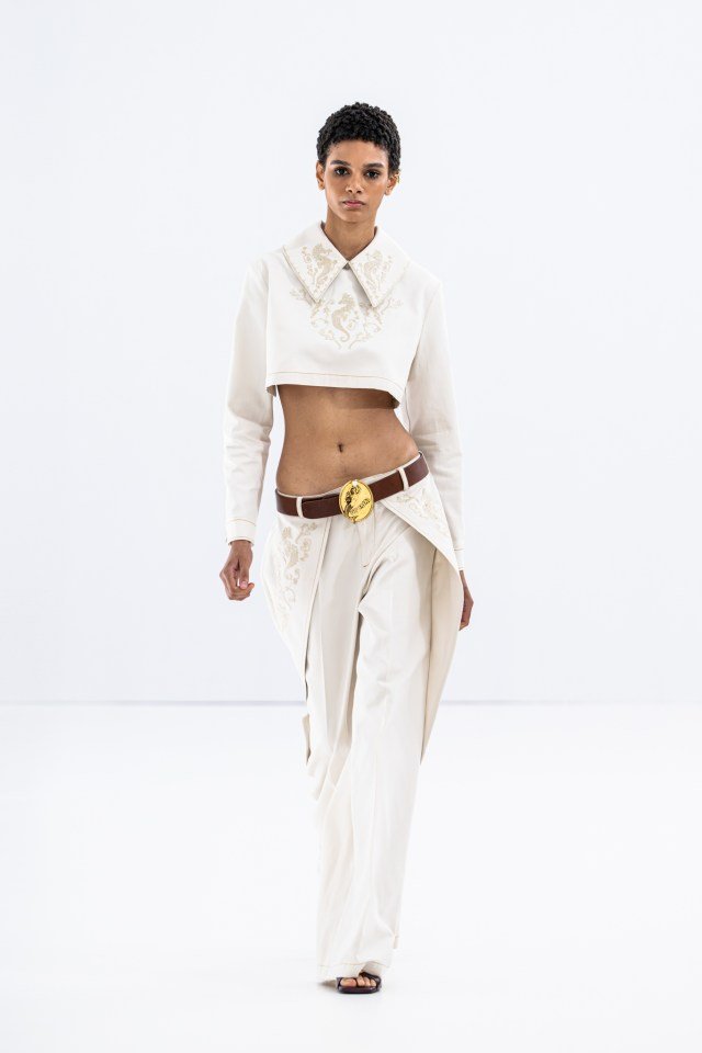 Modelo em passarela com conjunto branco, calça larga e top cropped, durante evento Milan Fashion Week SS26.