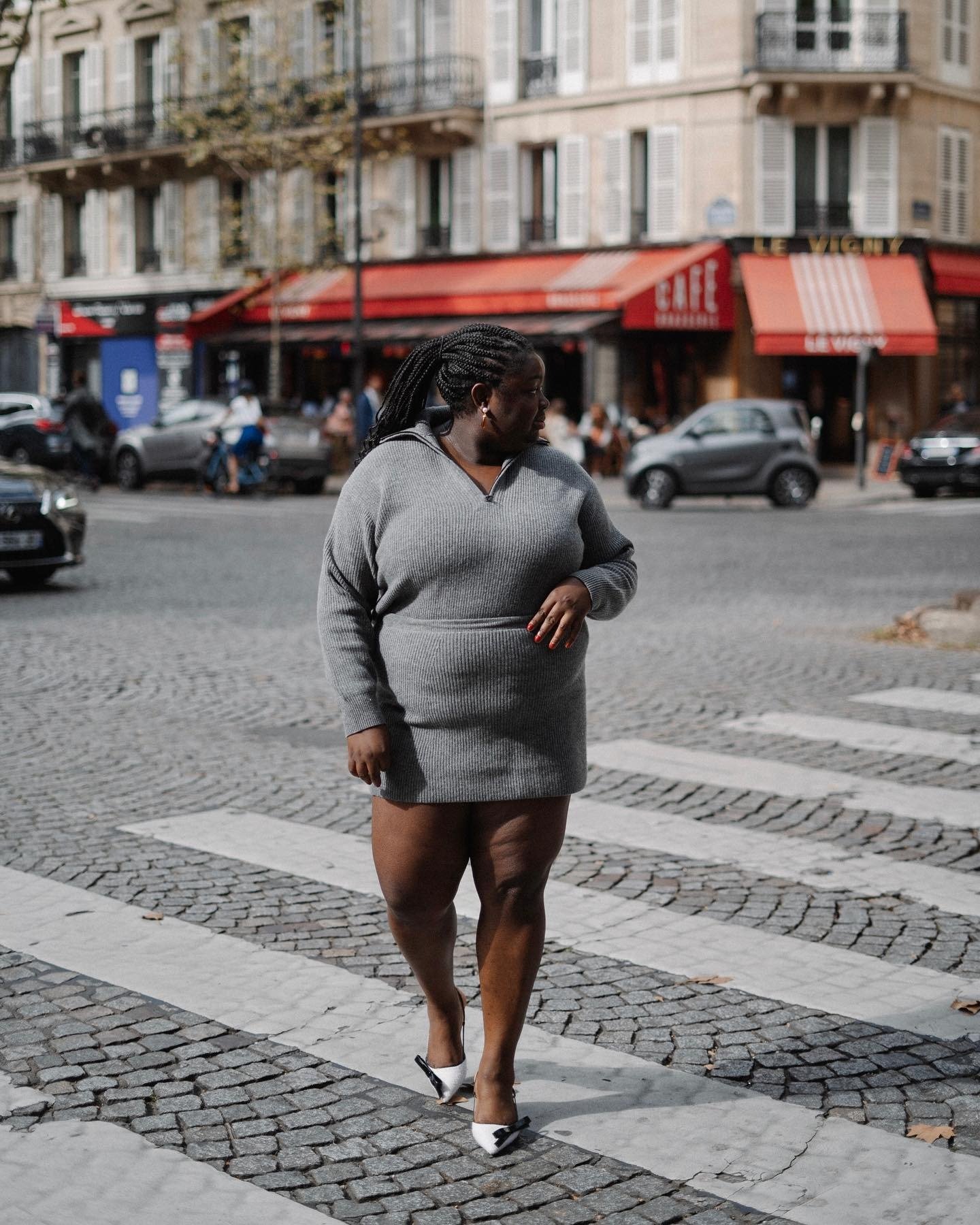 A blusa canelada básica, em tom cinza, destaca-se no visual moderno e elegante. Com um design que valoriza a silhueta, a peça é combinada com uma saia que complementa o look. O estilo é finalizado com sapatos brancos que trazem um toque de sofisticação.