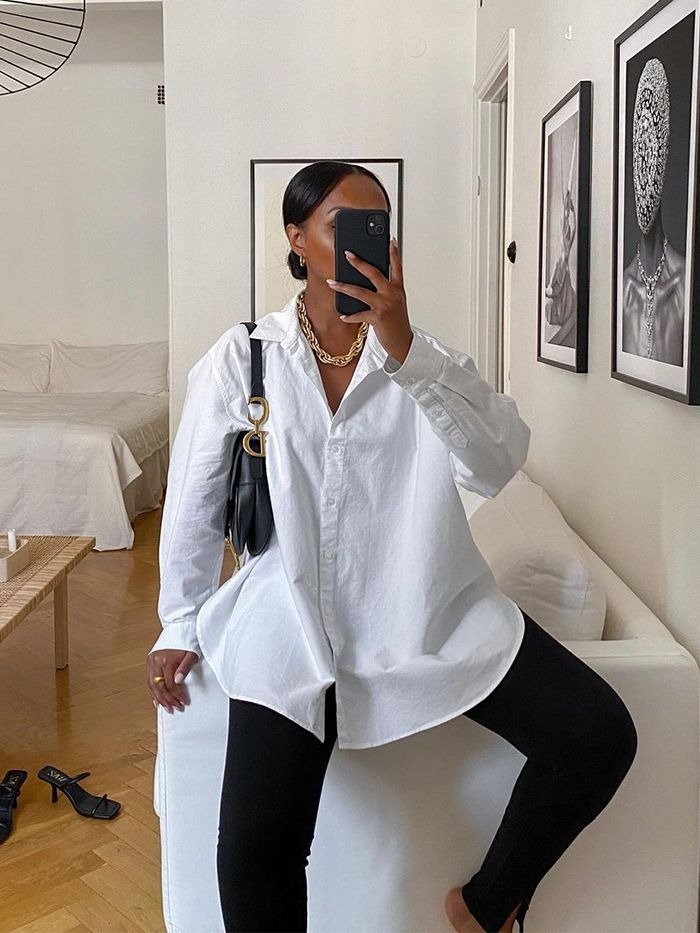 Look com calça legging apresenta uma combinação moderna e confortável. A peça preta se ajusta ao corpo, destacando a silhueta. A camisa branca oversized traz um toque de elegância.