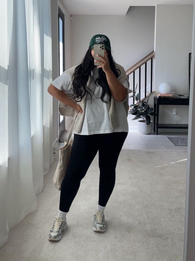 O looks com calça legging é moderno e confortável. A combinação de uma camiseta oversized branca com um colete neutro traz um toque casual e despojado.