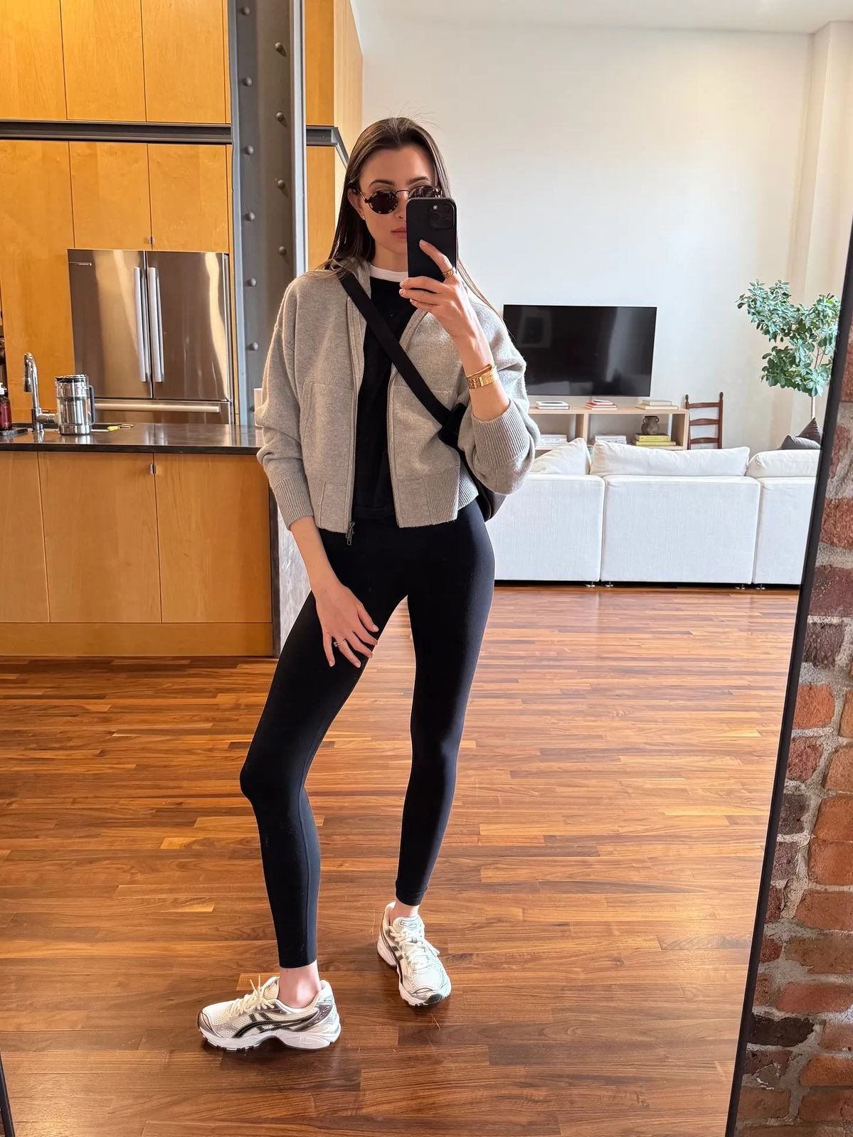 O looks com calça legging destaca um estilo moderno e confortável. A combinação de uma calça legging preta com um cropped cinza cria um visual equilibrado e casual.