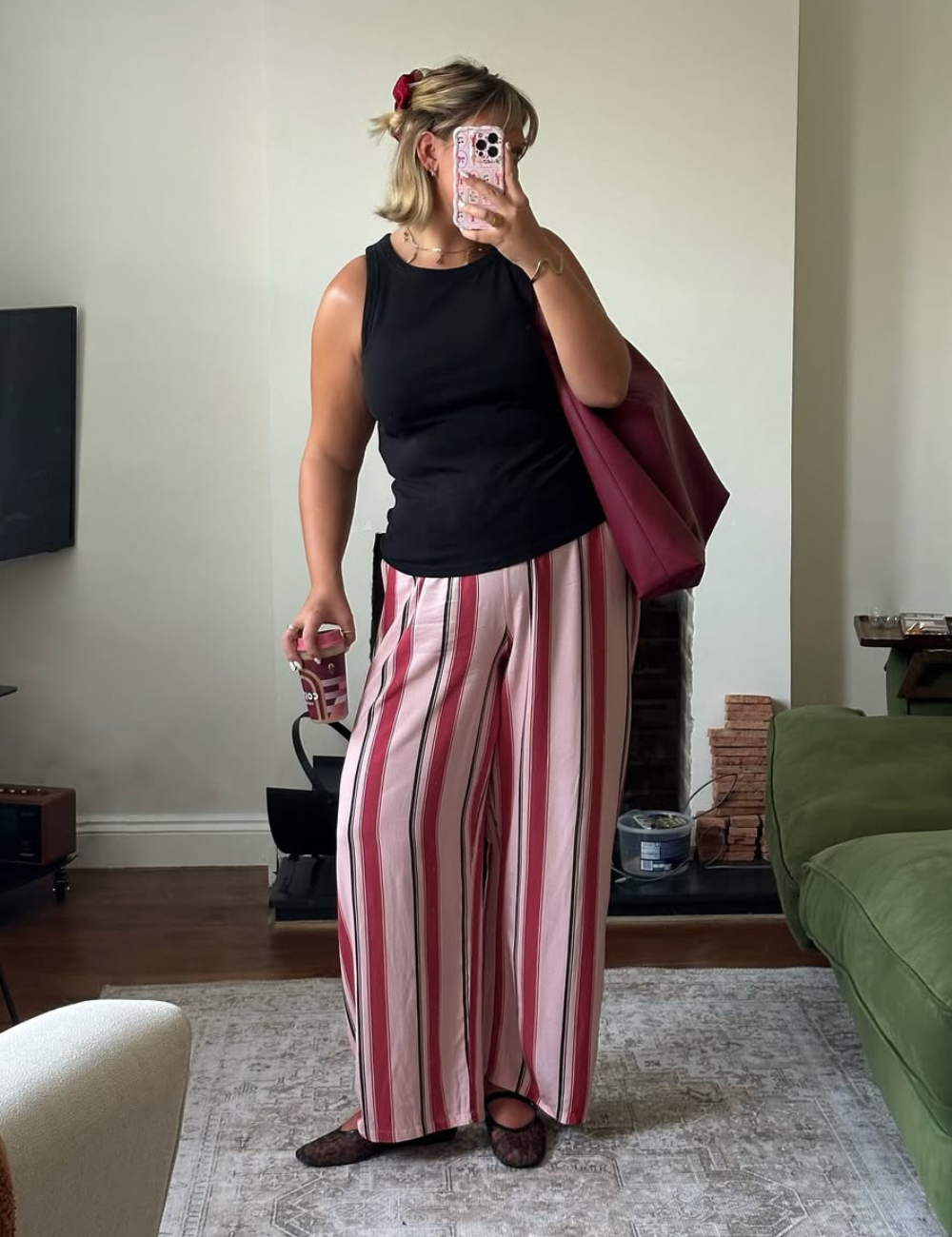 A combinação ideal de blusa para usar com calça pantalona pode variar, mas esta imagem ilustra uma escolha elegante. A pessoa veste uma blusa preta sem mangas, que contrasta bem com a calça pantalona listrada em tons de rosa e preto.