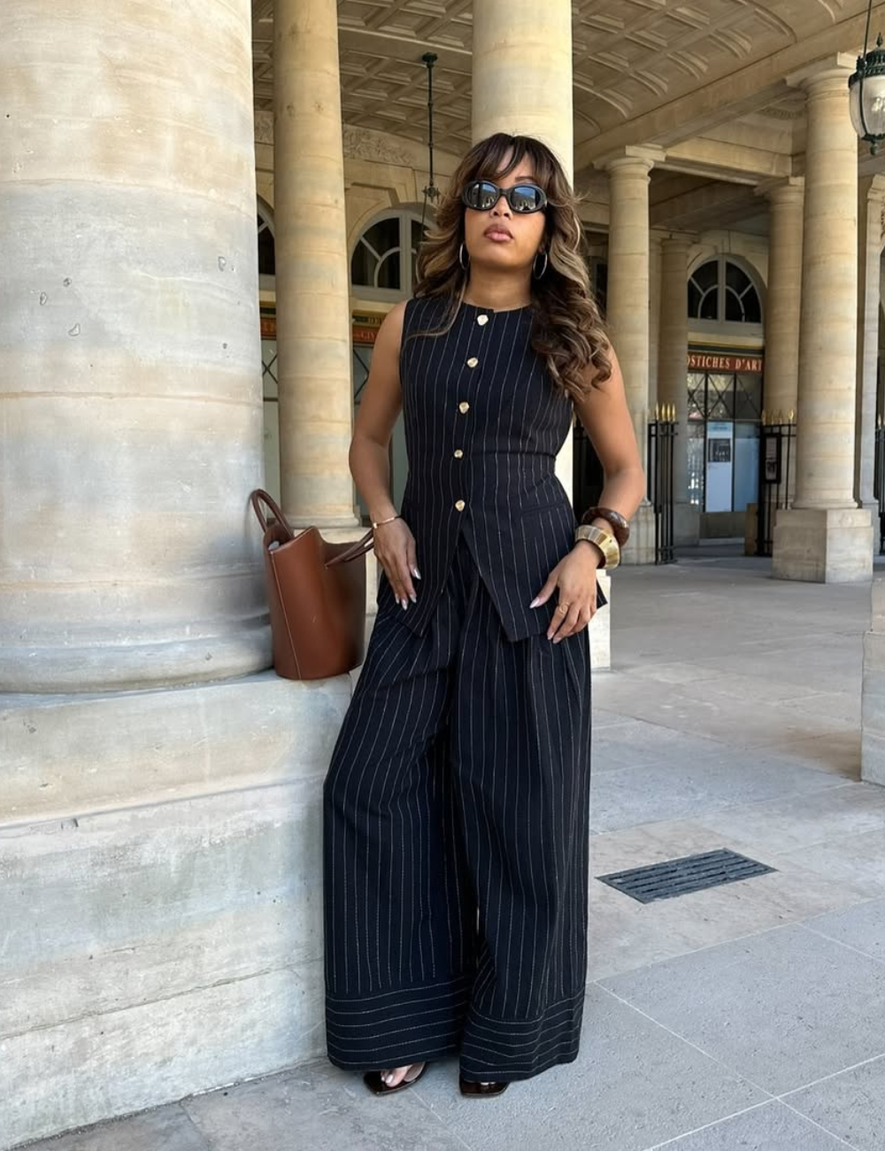 A combinação ideal para calça pantalona é uma blusa que valorize a silhueta. Nesta imagem, a modelo usa um conjunto de blusa sem mangas e calça pantalona listrada, que traz elegância e sofisticação. Os botões frontais adicionam um detalhe charmoso, enquan