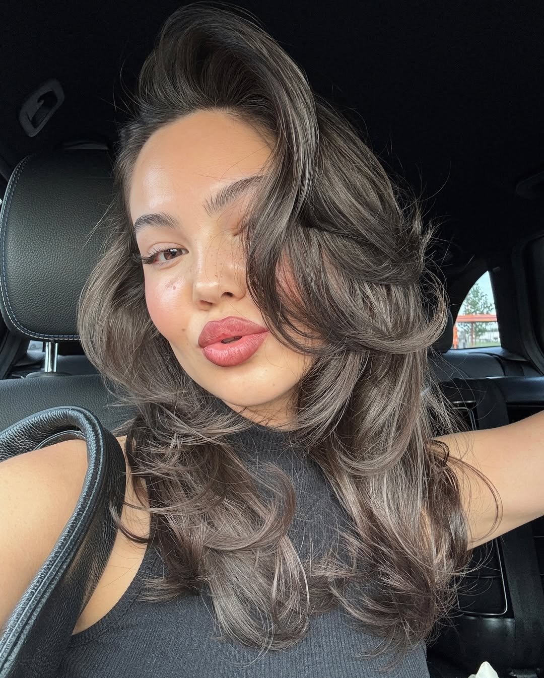 Cabelo volumoso e bem estilizado é o foco desta imagem, onde uma jovem exibe ondas soltas e naturais, criando um efeito de movimento. Como dar volume no cabelo