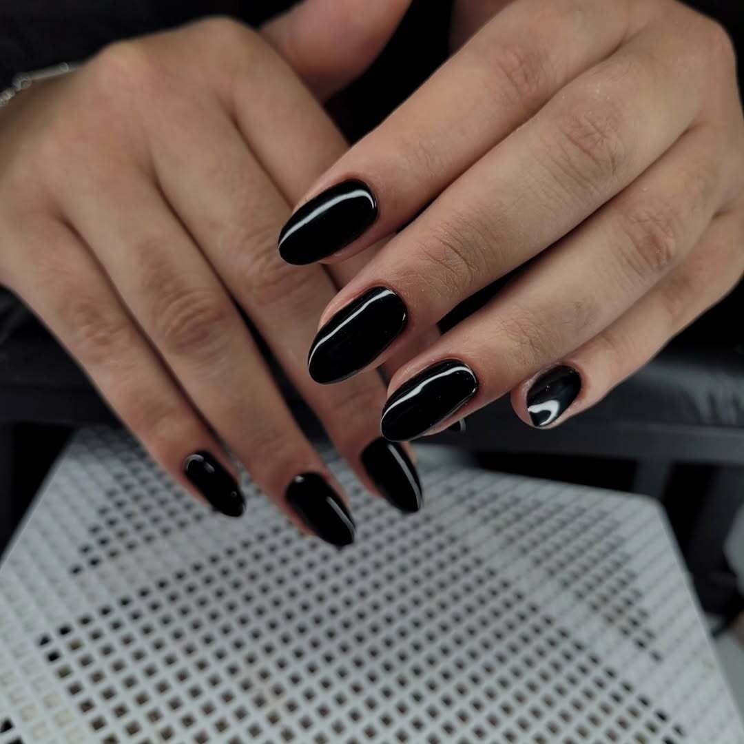 As unhas exibem um esmalte descasque na cor preta, com um acabamento brilhante e bem aplicado.