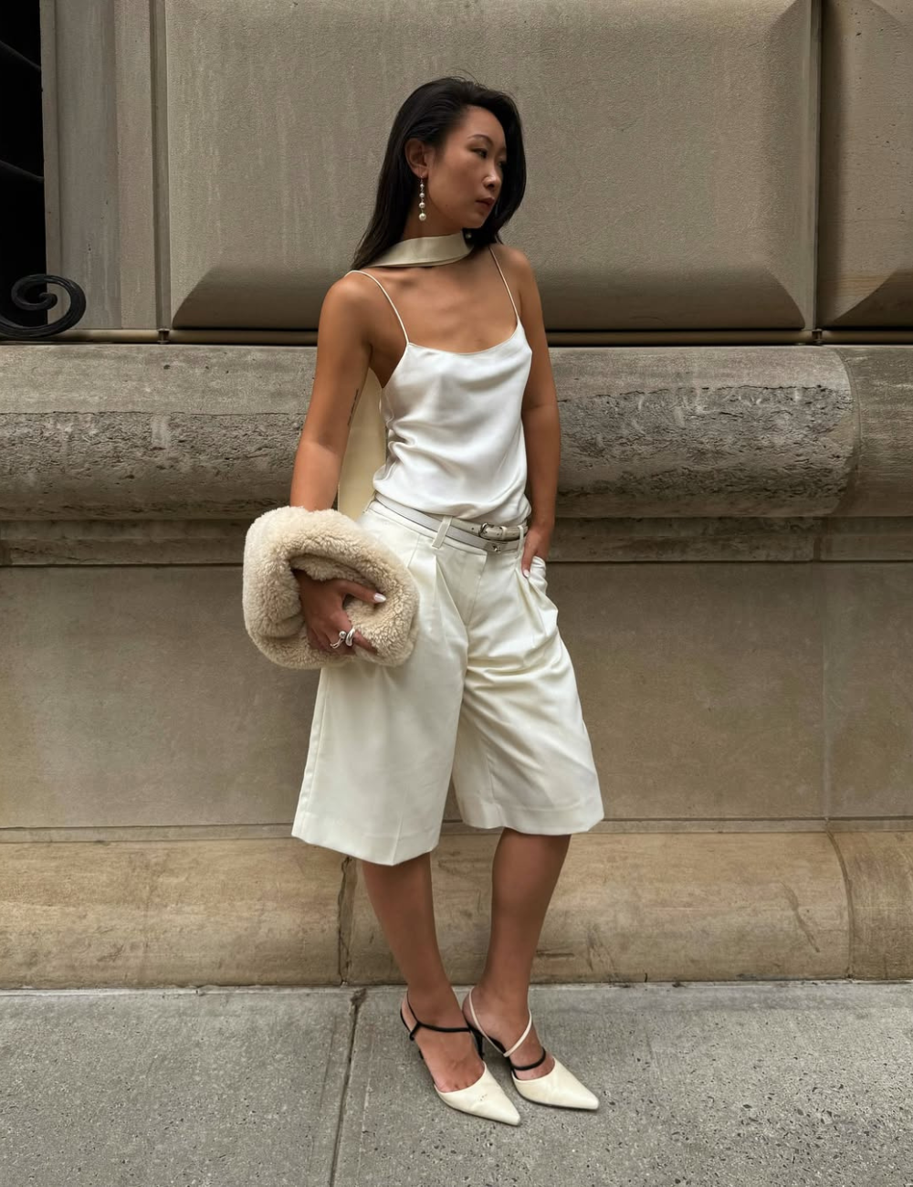 A bermuda feminina branca destaca-se por seu corte moderno e tecido fluido, ideal para compor looks elegantes. Combinada com uma blusa de cetim e acessórios sofisticados, como brincos de pérola e uma bolsa, cria uma estética refinada.