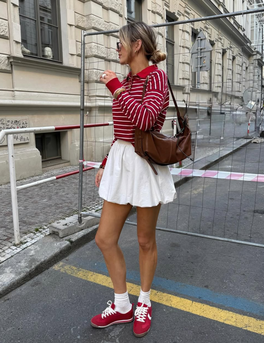 O uso de tênis vermelho pode transformar um look casual em uma declaração de estilo. Na imagem, a combinação de um suéter listrado em vermelho e branco com uma saia branca cria um contraste atraente.