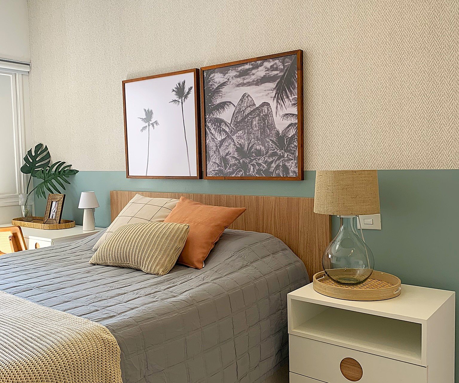 Quarto acolhedor com cama e almofadas em tons naturais, quadros de paisagens e luminária, promovendo conforto sensorial.