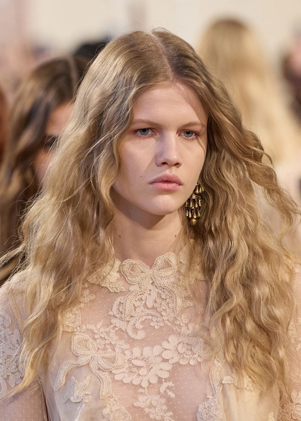 Mulher usando melena boho, um dos cortes de cabelo feminino para 2026. Os cabelos longos e ondulados emolduram o rosto.