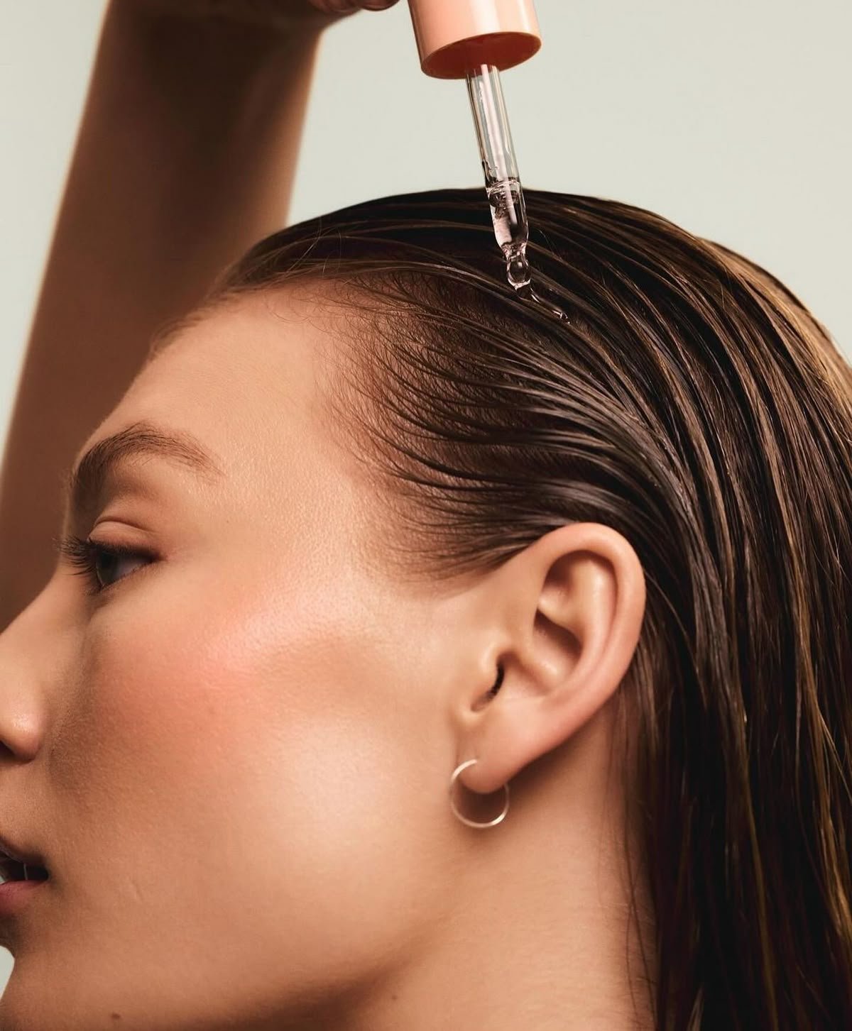 Pessoa aplicando produto em gotas de cuidar do couro cabeludo com conta-gotas para cuidar da pele e cabelo.