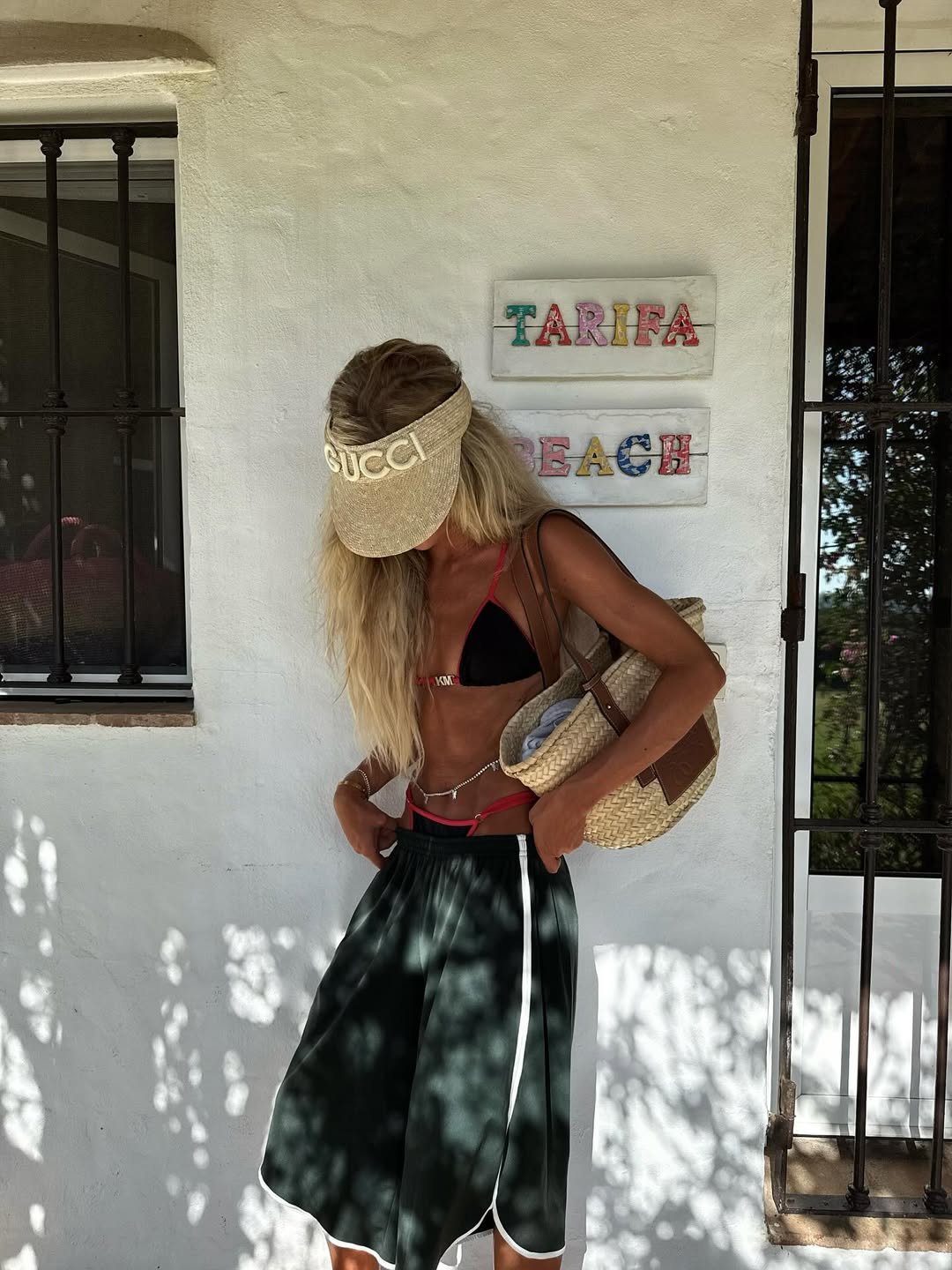 Mulher com chapéu de aba larga, biquíni preto e saia esvoaçante, estilo inspirado no surf.