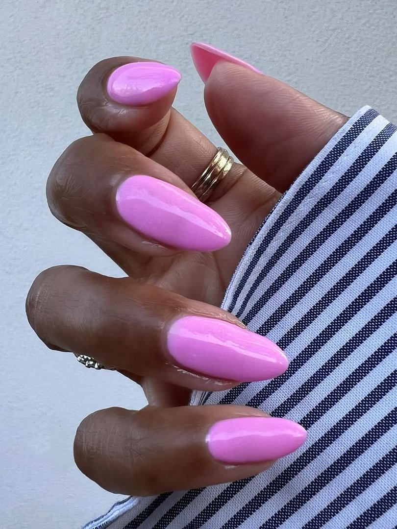 Unhas com esmalte rosa, tendência primavera-verão 2026, sobre tecido listrado.