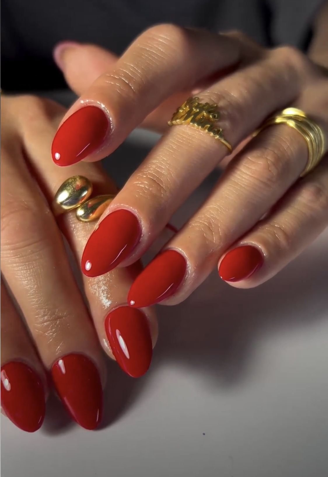 Unhas vermelhas esmaltadas com anéis dourados destacam tendências de esmalte primavera verão 2026.