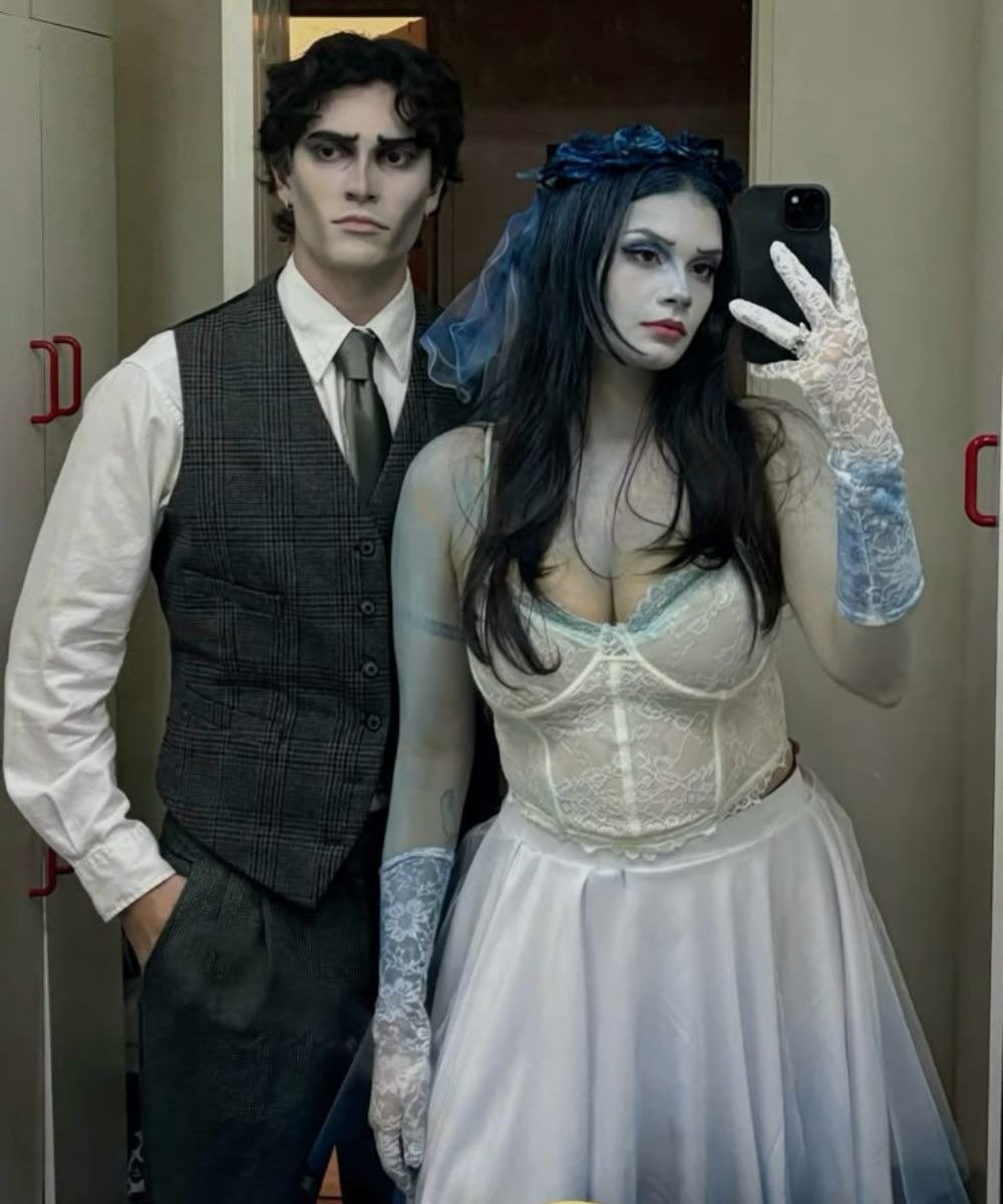 Casal usando fantasia de Halloween inspirada em Noiva Cadáver, com a mulher vestindo um vestido branco de tule e corpete rendado.