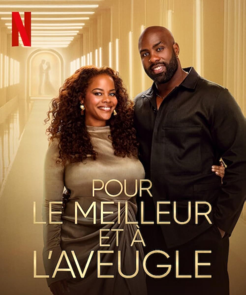 Casal sorridente em um corredor iluminado com cartaz de ''Casamento as cegas: França'', uma indicação de filmes e séries novas.