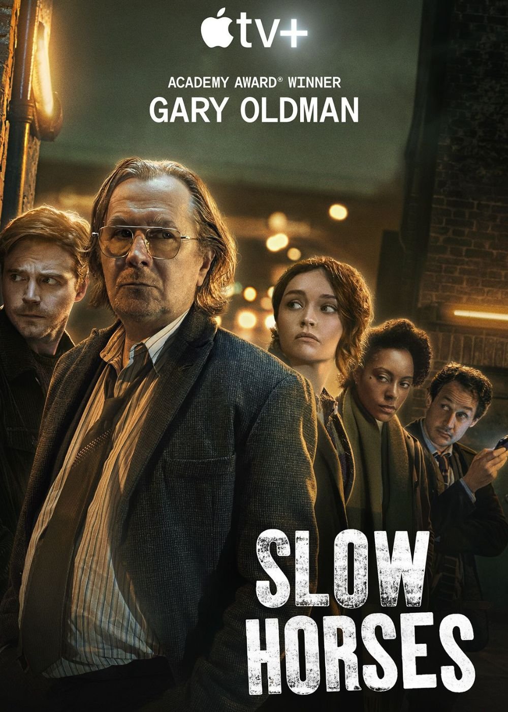 Pessoas em rua escura do drama “Slow Horses”, uma série nova com Gary Oldman no Apple TV+.