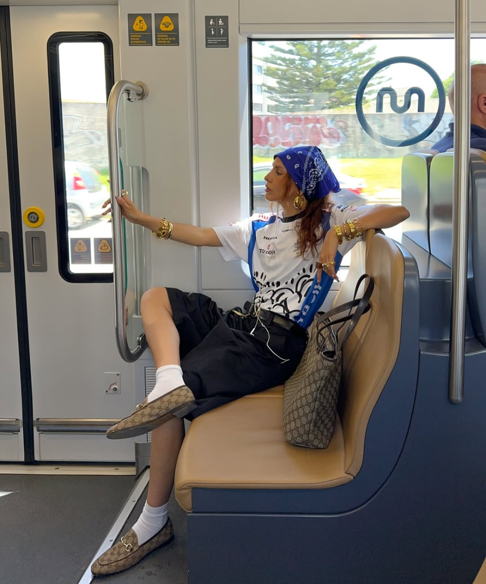 Pessoa descontraída em trem segurando barra, com bandana azul e roupa casual estilosa.