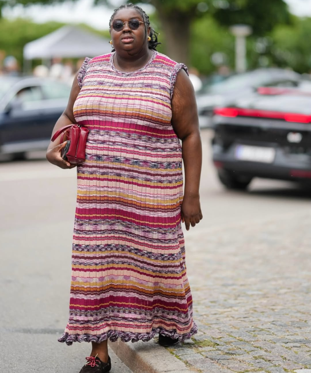 Vestido listrado em tons de rosa e roxo, complementado por bolsa vermelha, criando ideias de look elegantes.