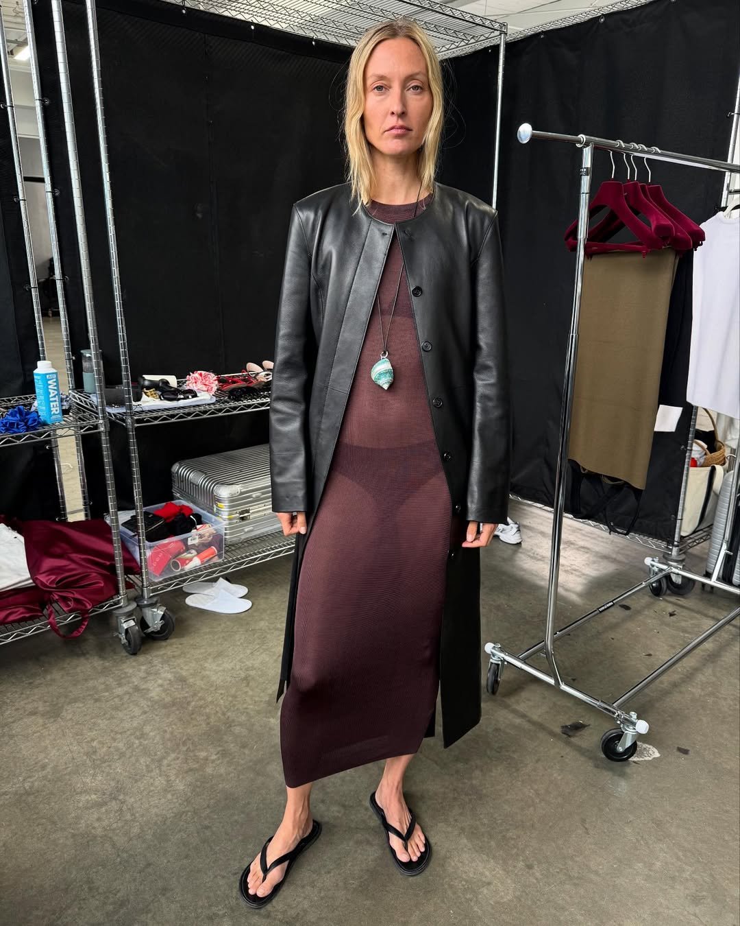 Modelo em sandálias, vestido transparente e casaco de couro, combinando elegância com um toque surf na moda.