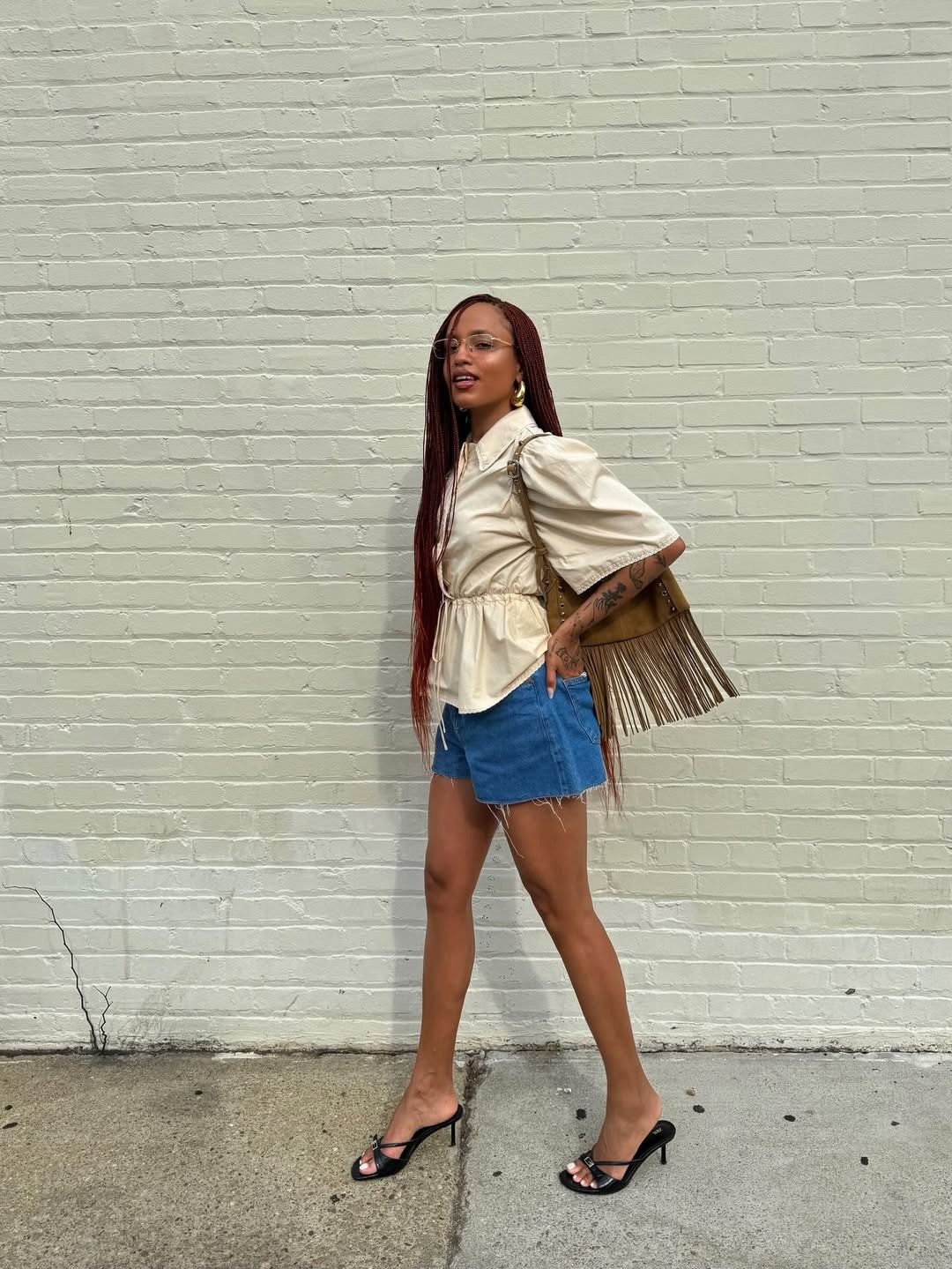 Mulher usando look com bermuda jeans curta e blusa clara, destacando um estilo moderno e descontraído.