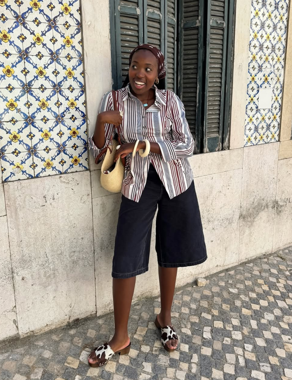 O look com camisa listrada feminina destaca uma combinação de estilo e conforto. A camisa, com listras em tons suaves, é combinada com shorts escuros, criando um equilíbrio moderno.