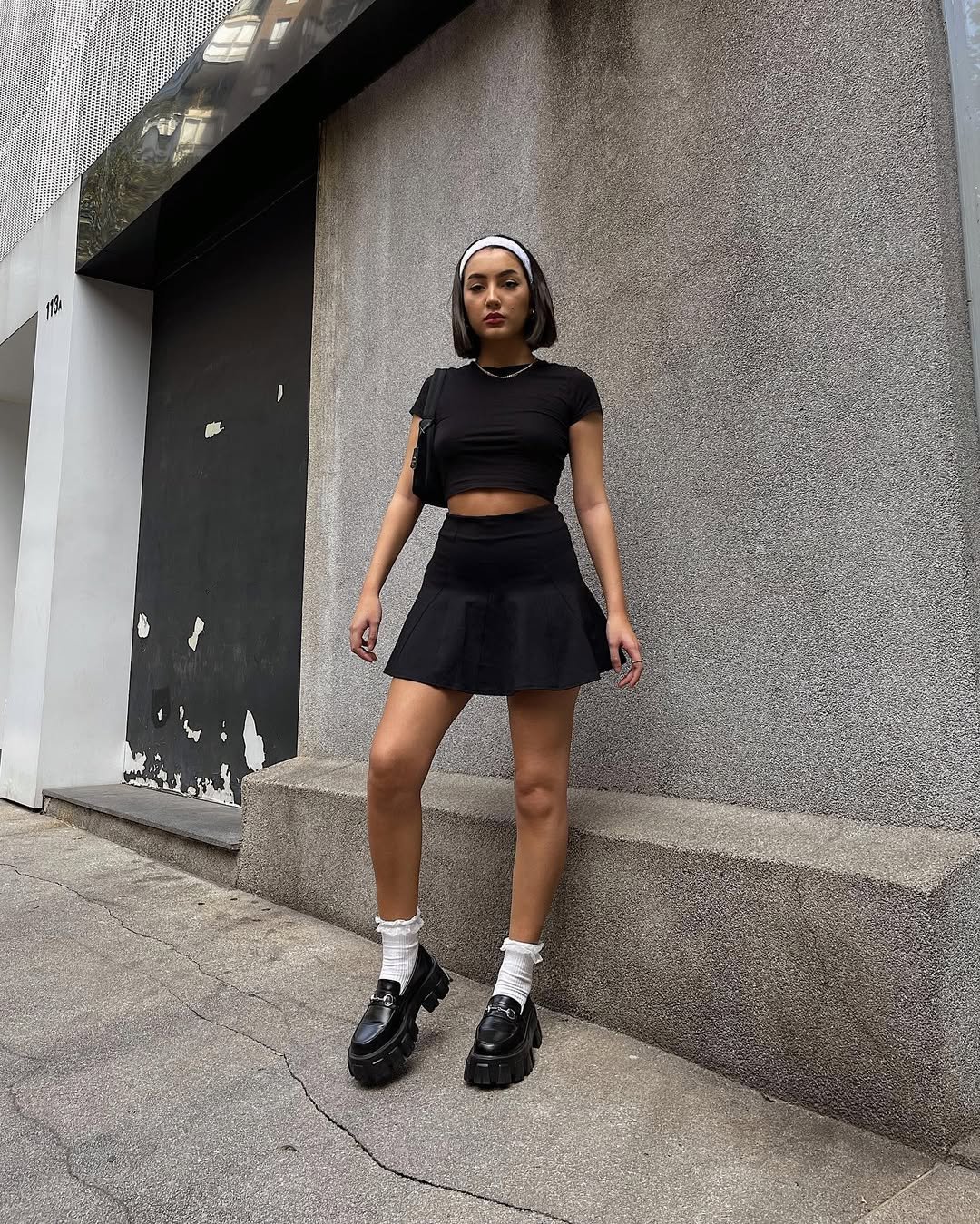 Mulher ensinando a usar looks com mocassim tratorado! Combinado com saia preta, top cropped preto e meias brancas.