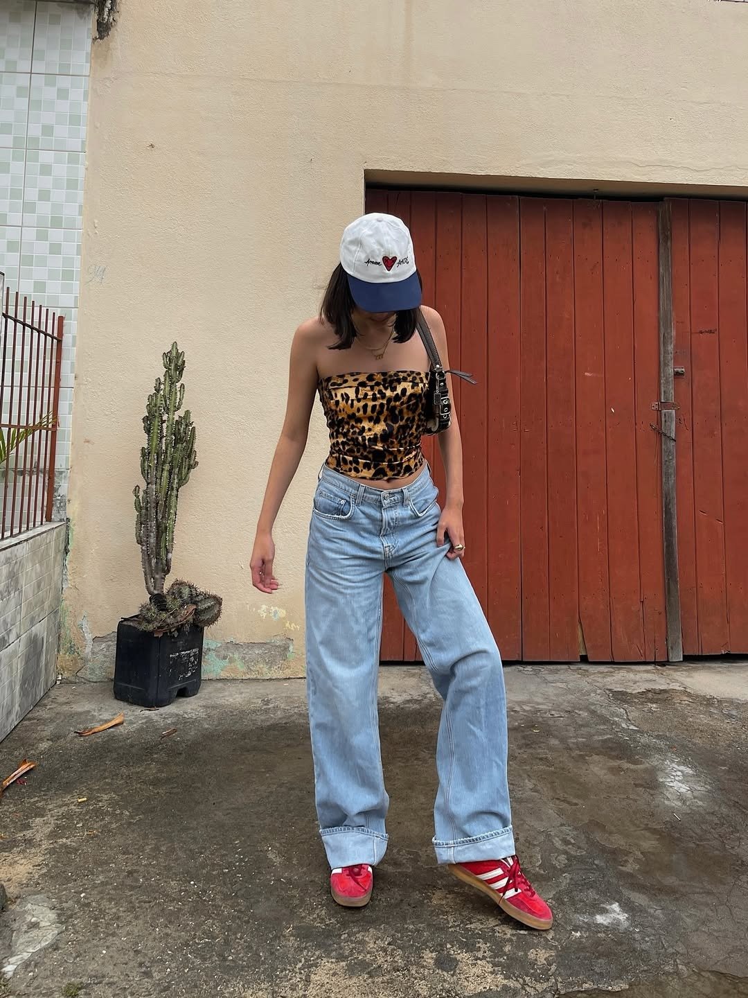 Mulher com look ideal para barzinho à noite com blusa de animal print e calça jeans oversized.