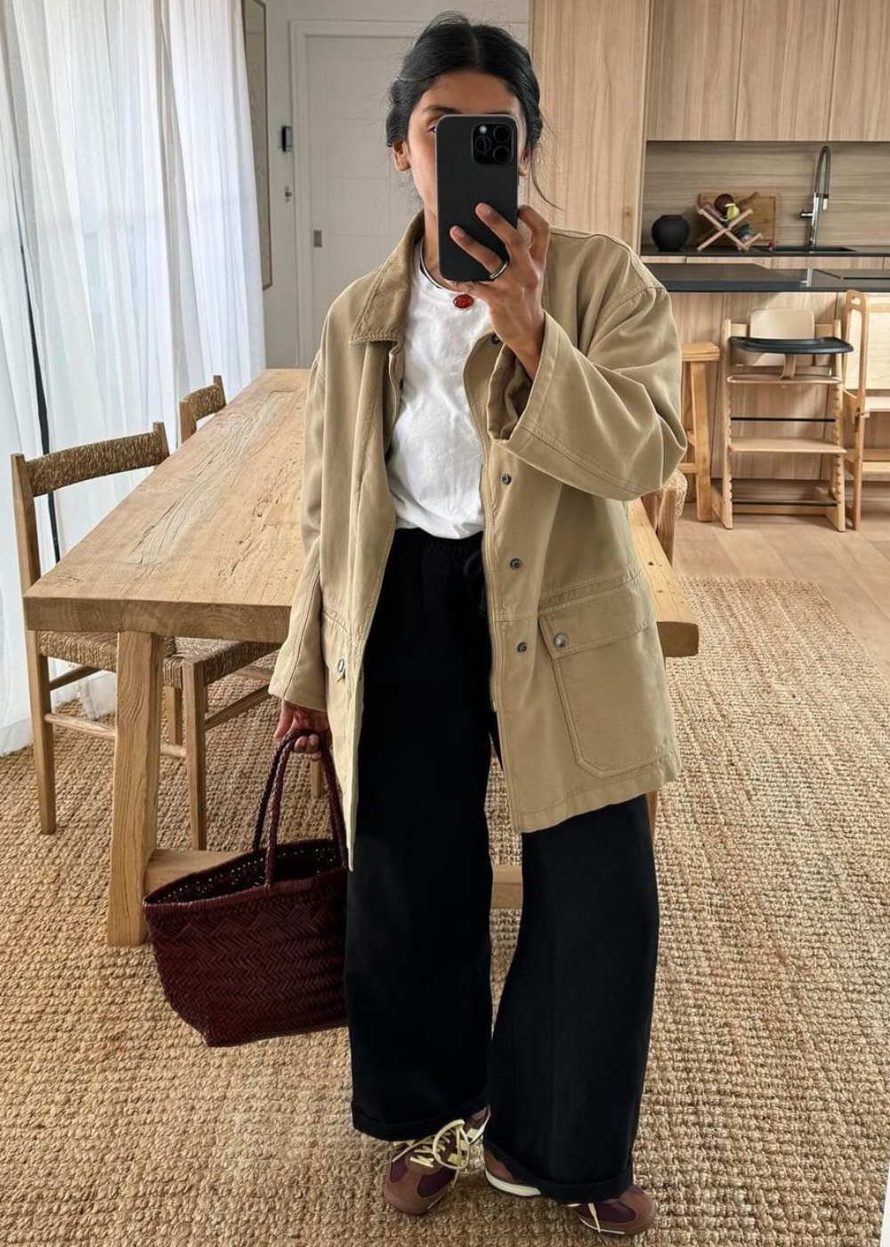 O look apresenta um estilo casual e contemporâneo, com destaque para o modelo adidas SL 72, que combina conforto e estética. A combinação de uma jaqueta oversized em tom bege, uma camiseta branca e calças largas pretas cria um contraste elegante.