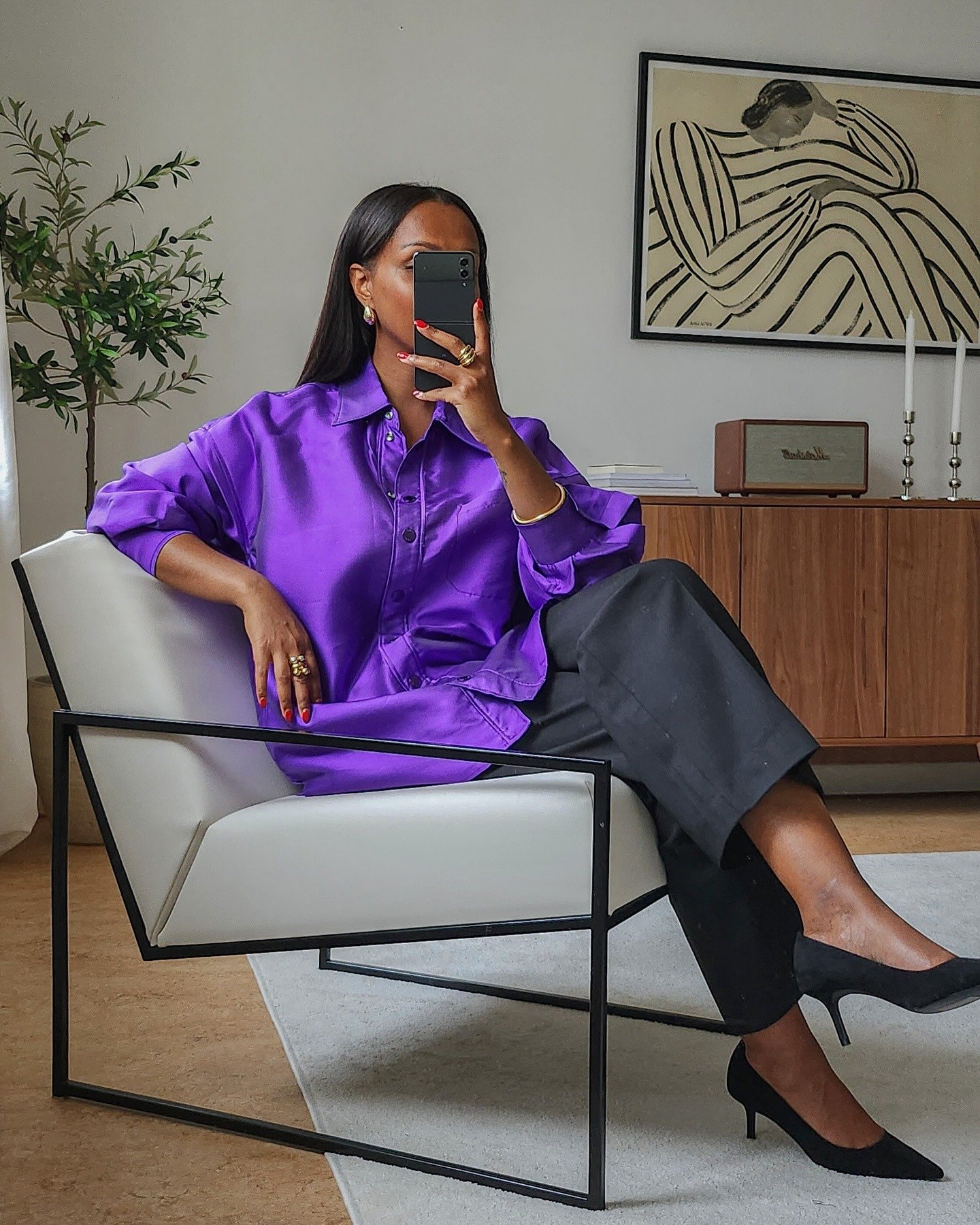 Looks coloridos para trabalhar com uma camisa roxa de seda que traz sofisticação e modernidade. A combinação com calças pretas amplas equilibra o visual, enquanto os sapatos de salto preto adicionam elegância.