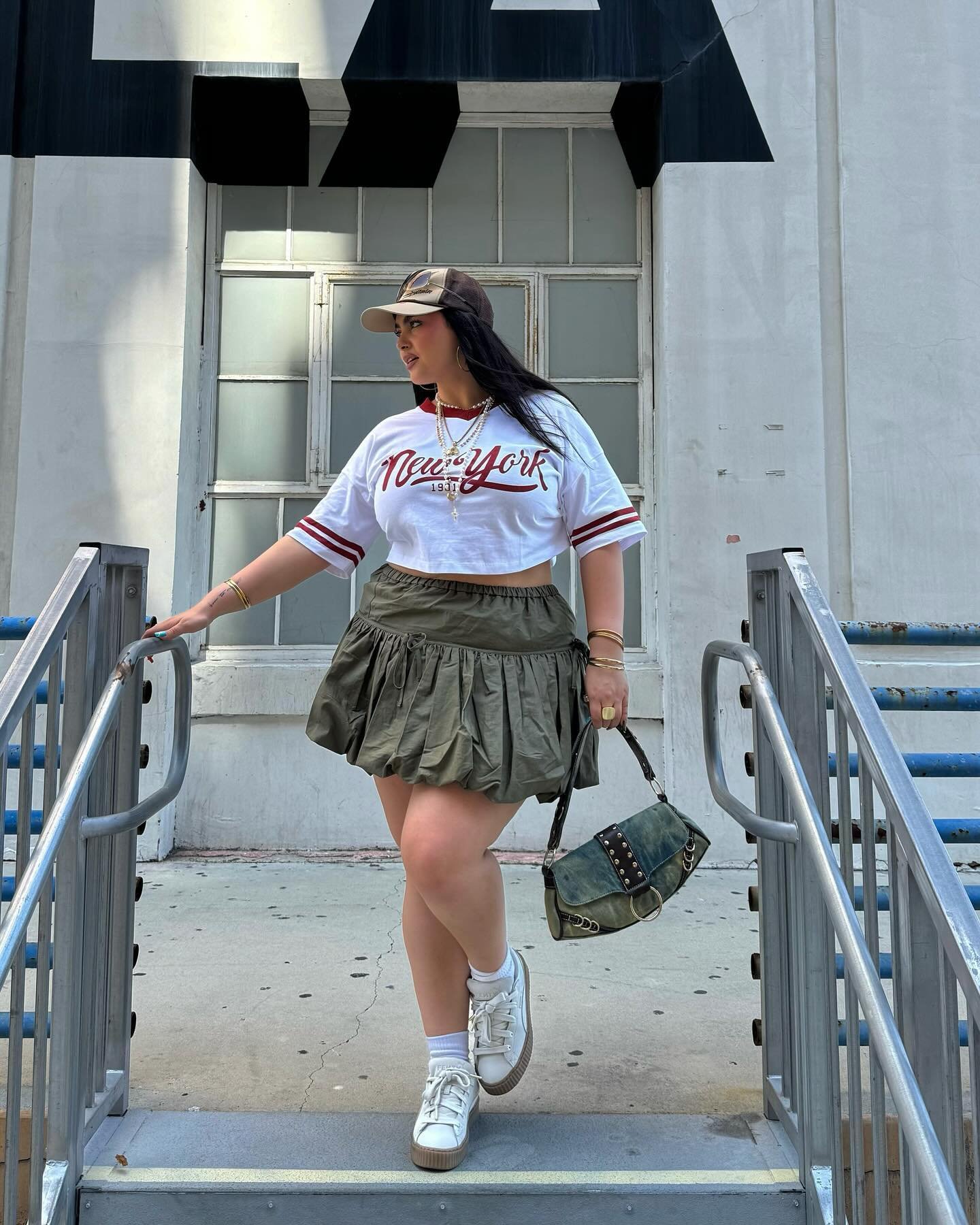 Mulher com blusa cropped,saia utilitária, acessórios e tênis branco.