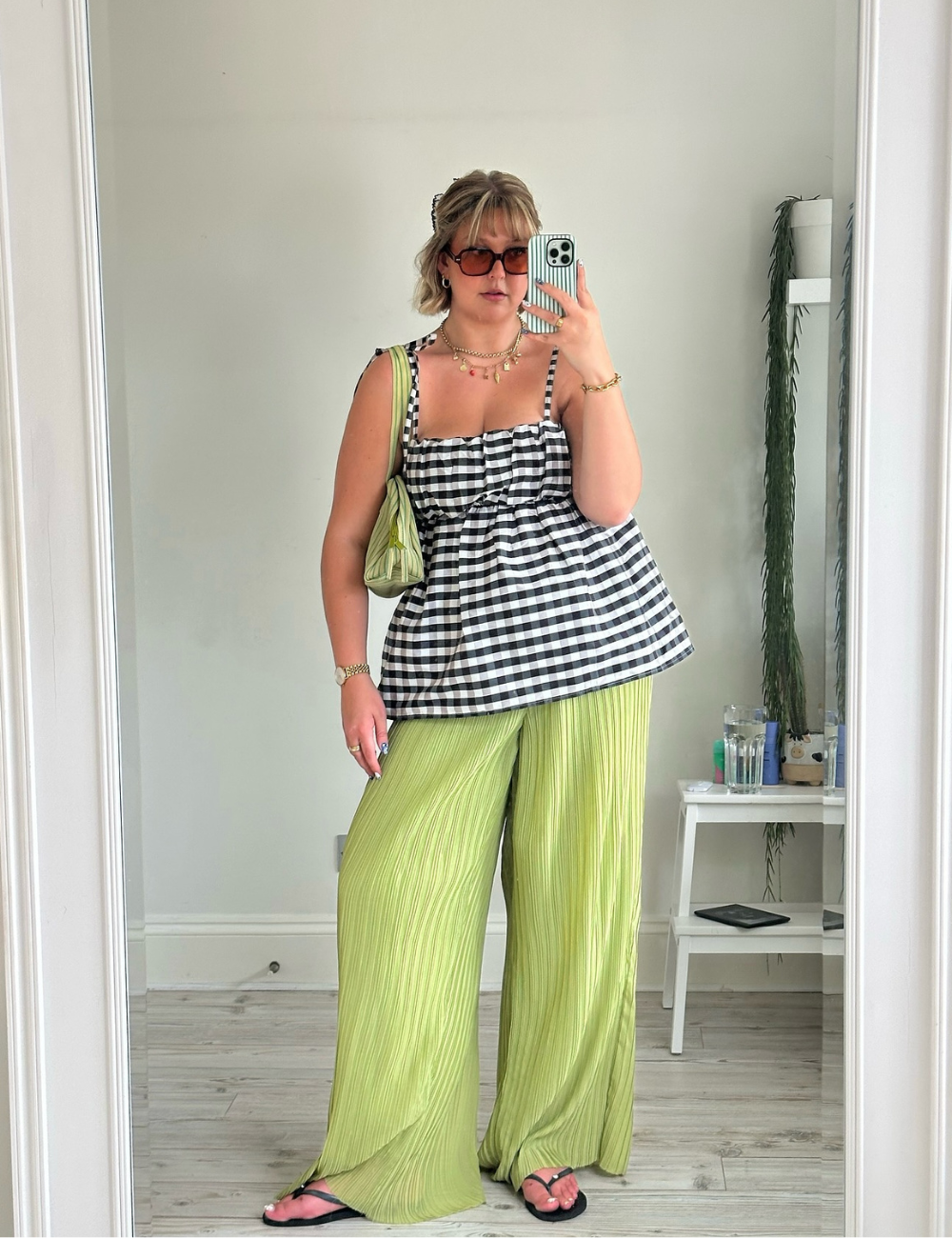 Pessoa em um look casual com blusa xadrez, calça verde ampla e chinelo preto.