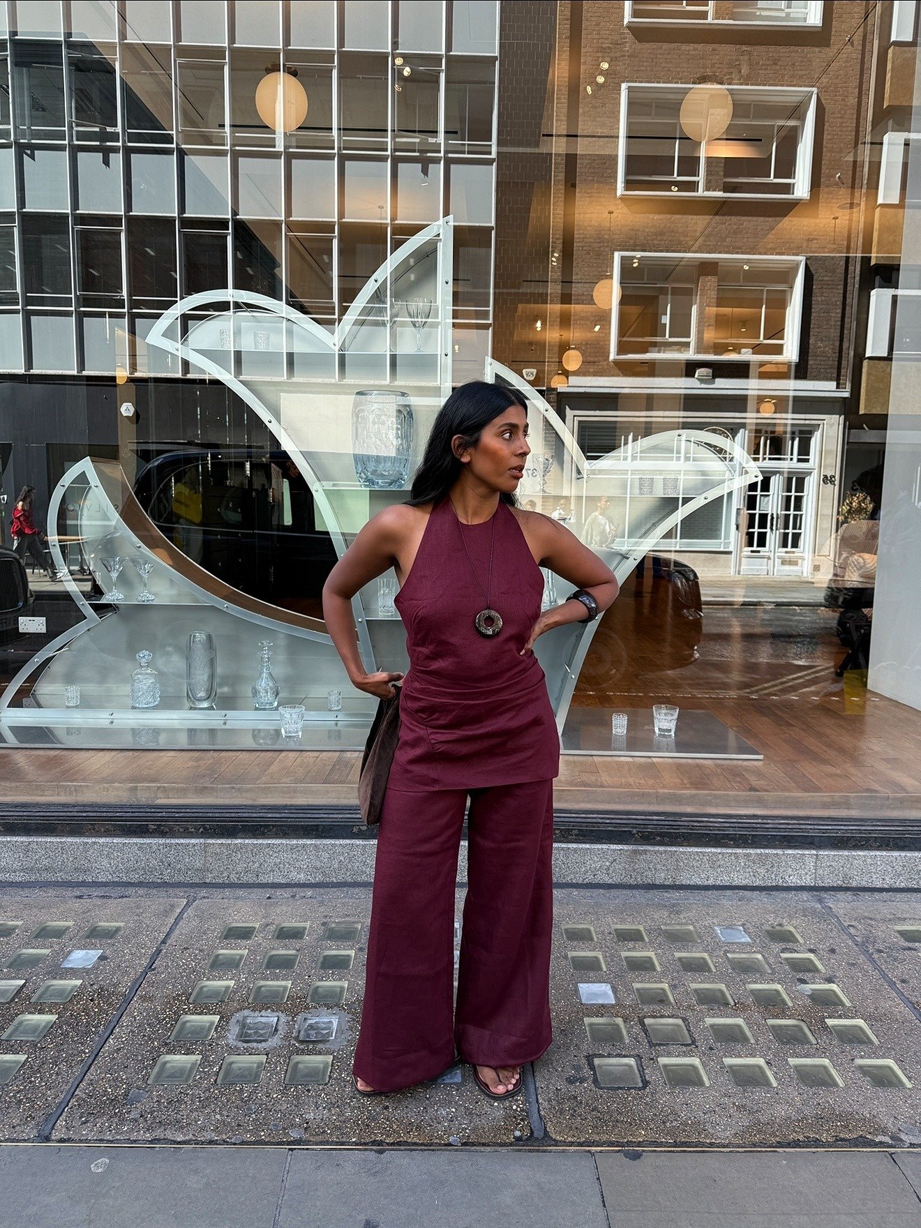 O look com sandália de dedo apresenta uma combinação elegante e casual, destacando um macacão na tonalidade vinho, que valoriza a silhueta. A peça, com decote em V e cintura marcada, é complementada por uma sandália de dedo, ideal para dias quentes.