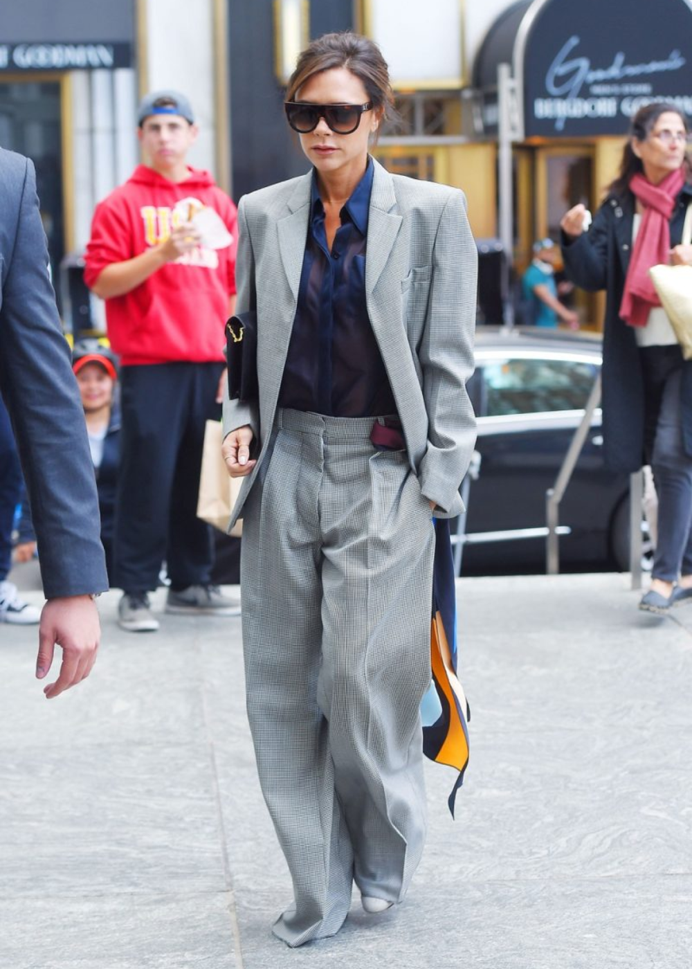 O look com terninho apresenta um estilo sofisticado e moderno, destacando uma combinação de blazer oversized em padrão xadrez e calças largas. A camisa de seda preta adiciona um toque de elegância, enquanto os óculos escuros complementam o visual.