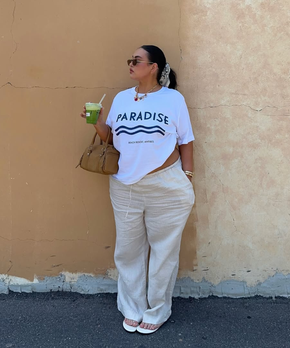 Pessoa usando camiseta branca e calça larga bege, segurando bebida verde. Look casual ideal para dias quentes.