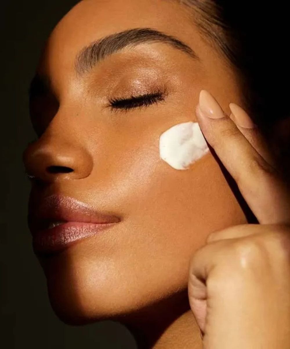 Uma mulher aplicando o melhor protetor solar para o rosto, destacando a importância desse cuidado na rotina de beleza.