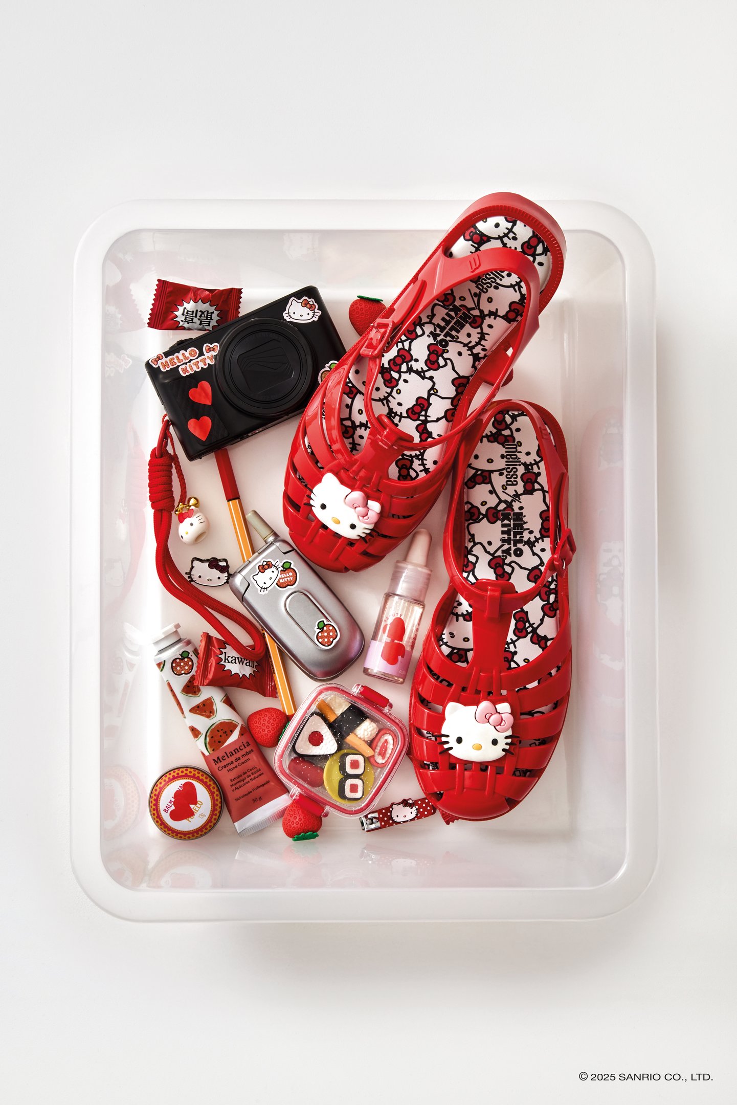 Sandálias vermelhas Melissa com tema Hello Kitty, cercadas por itens e acessórios personalizados. collab Melissa e Hello Kitty