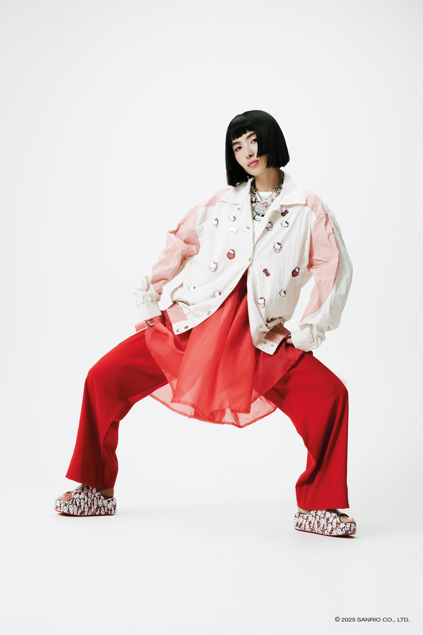 Modelo posa com roupa e sapatos Melissa, com estampa de Hello Kitty, em tons vermelho e branco. collab Melissa e Hello Kitty