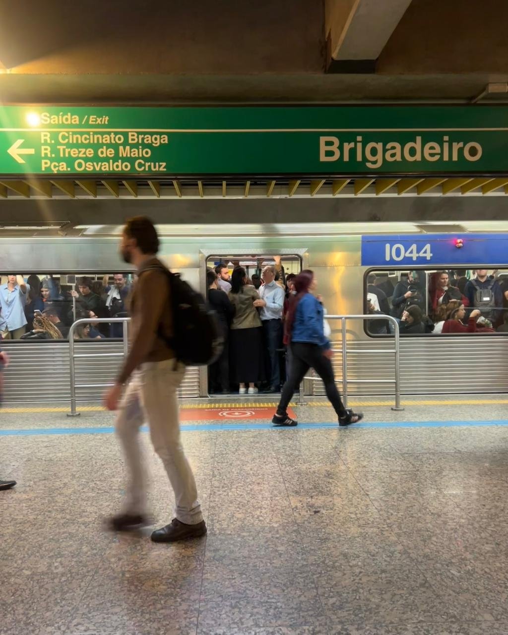Estação de metrô Brigadeira, lotada, com pessoas entrando e saindo do transporte público.