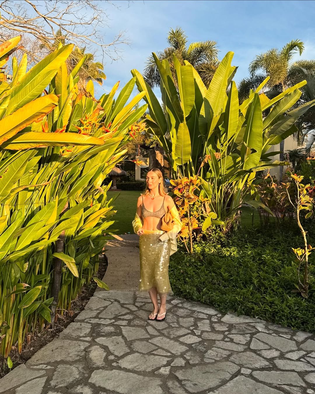 Mulher com roupa estilo praia em jardim, refletindo a influência do surf na moda.